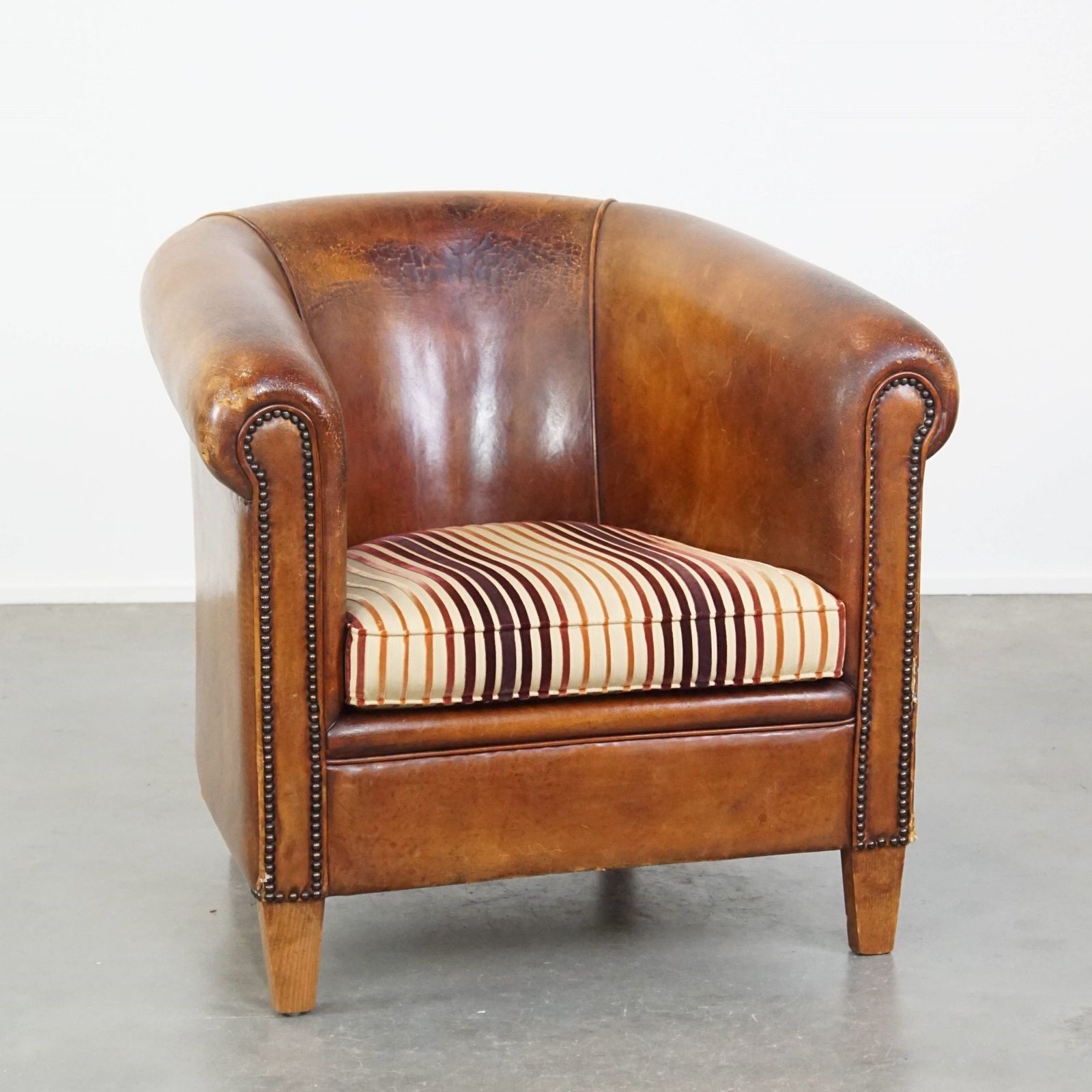 Characterful Vintage Cognac Colored Club Chair Made Of Sheepskin With A Colorful Fabric Seat Cushion