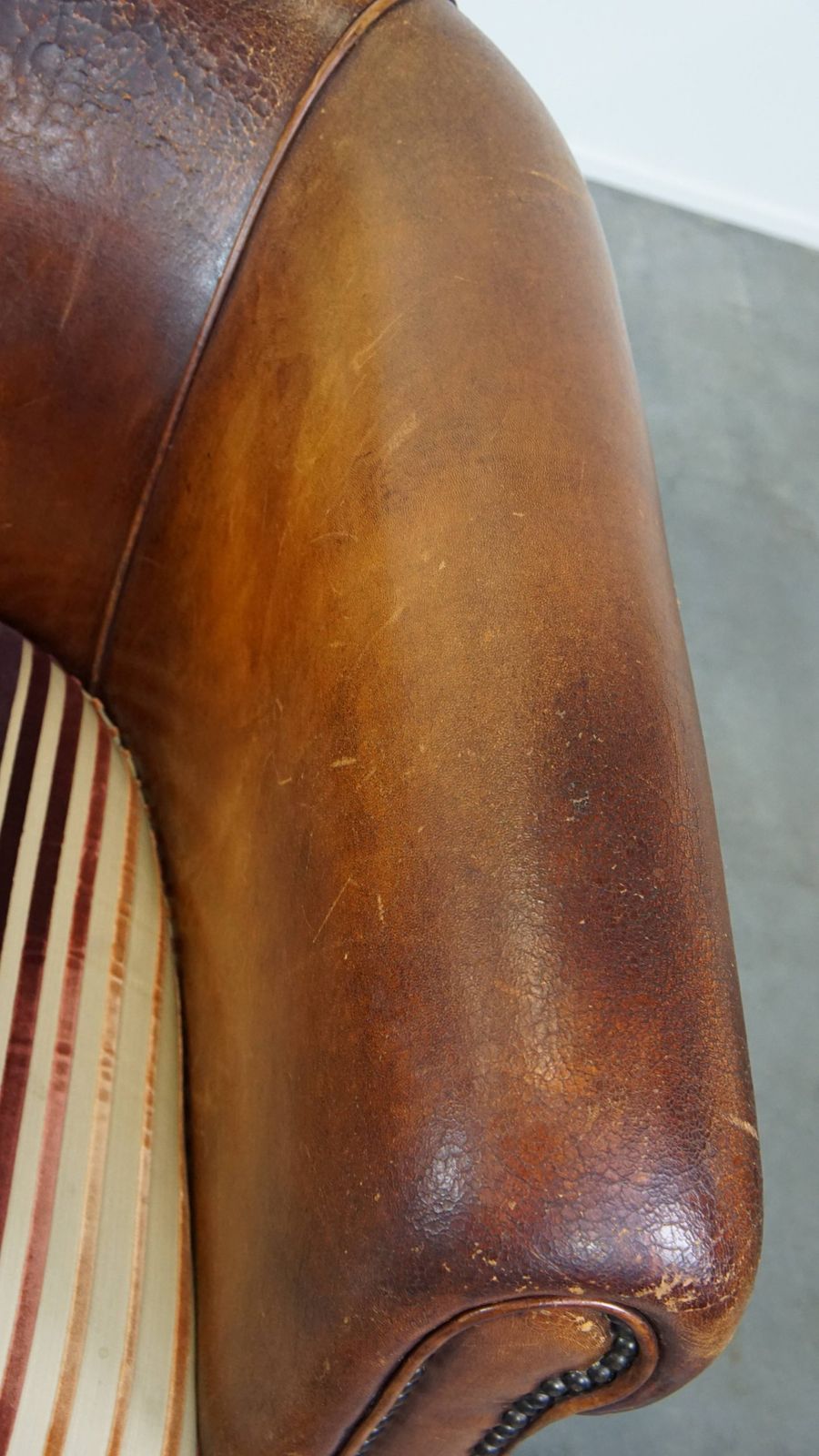 Characterful Vintage Cognac Colored Club Chair Made Of Sheepskin With A Colorful Fabric Seat Cushion photo vintage