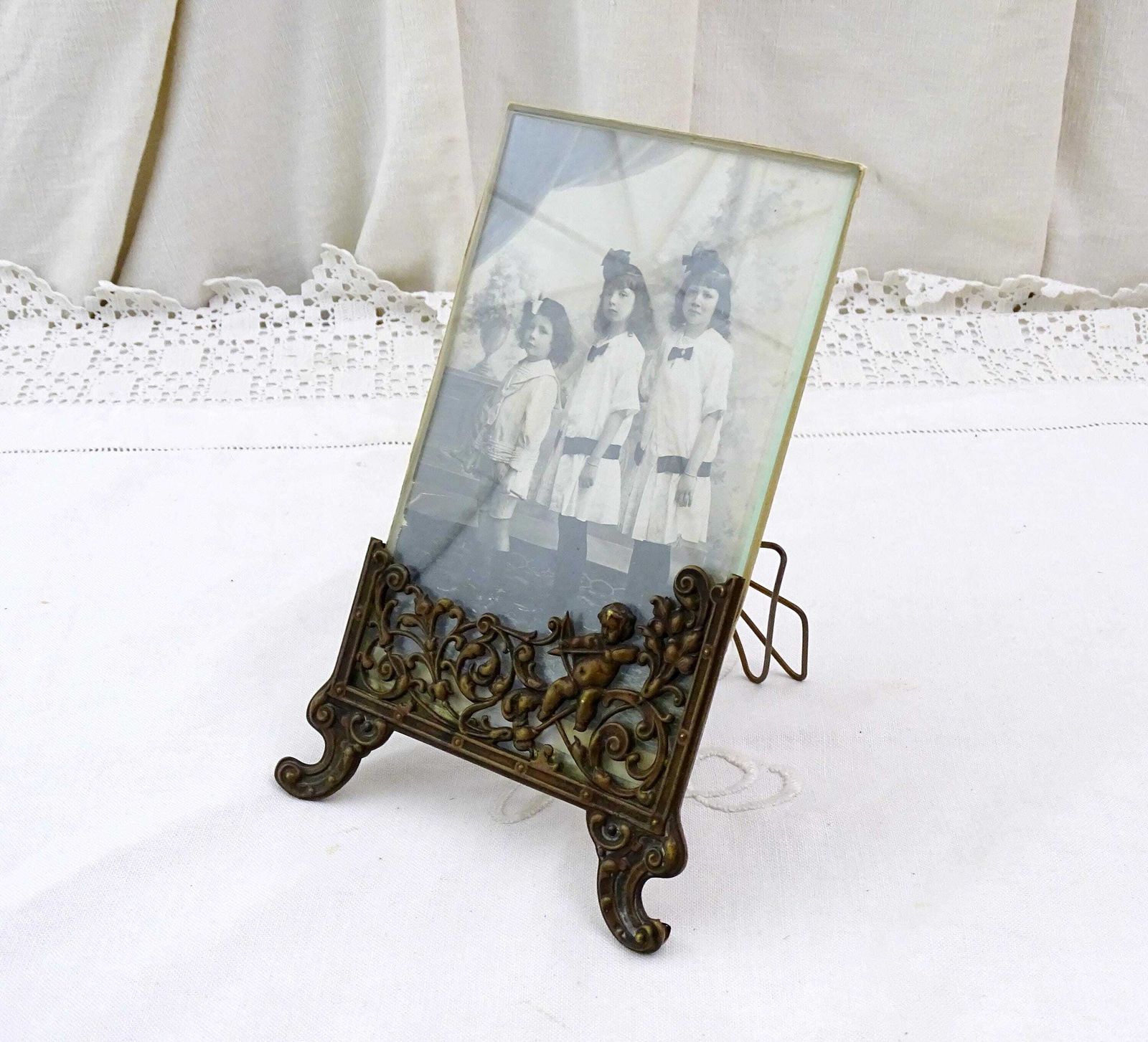 Antieke Franse Vrijstaande Fotolijst Met Cherub In Bronskleurig Reliëfmetaal En Zwart Witfoto Van Zusjes En Broertje photo for sale