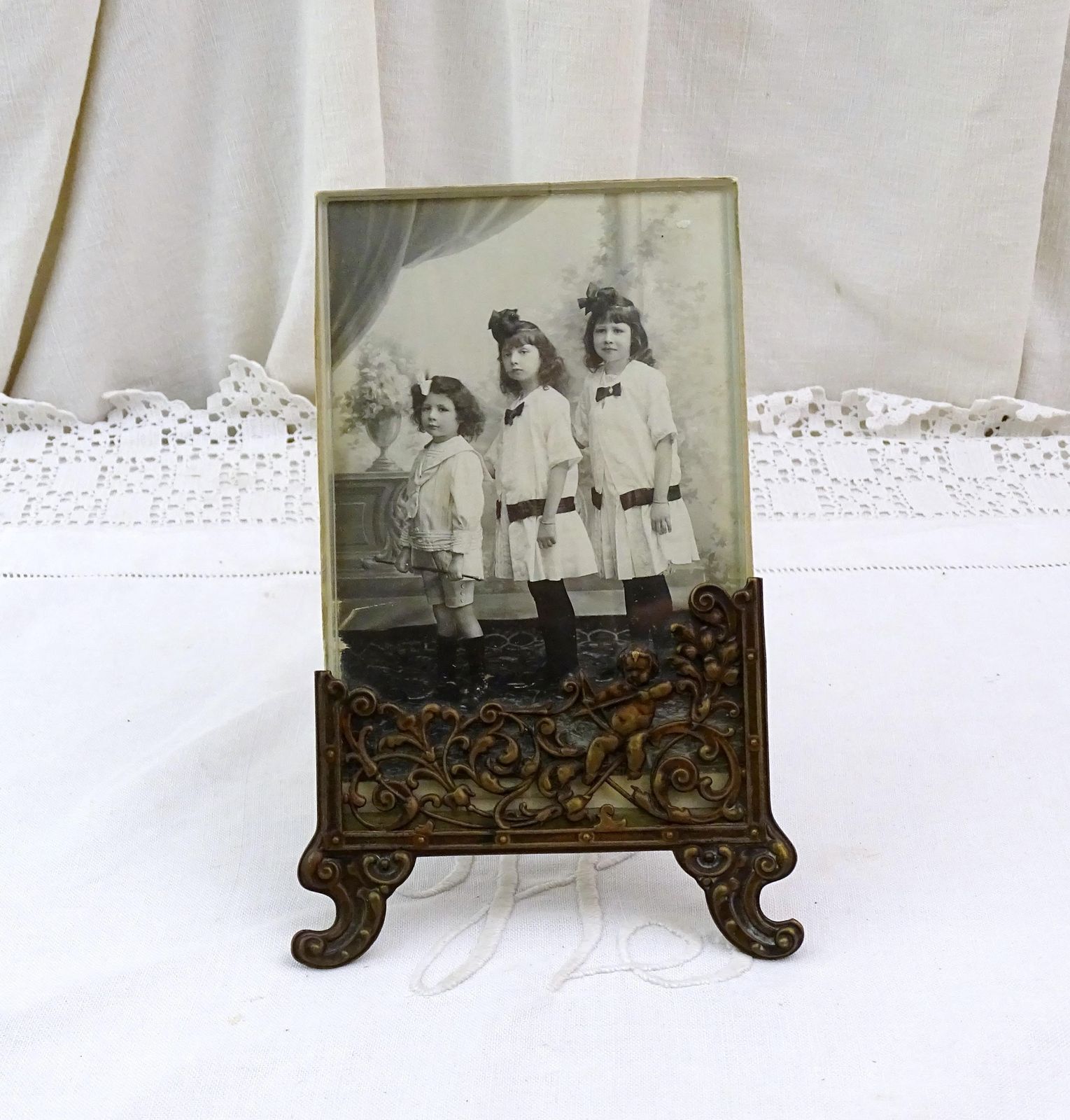 Antique French Free Standing Frame Decorated With A Cherub In Bronze Tone Embossed Metal And Black And White Photograph Sisters And Brother photo vintage