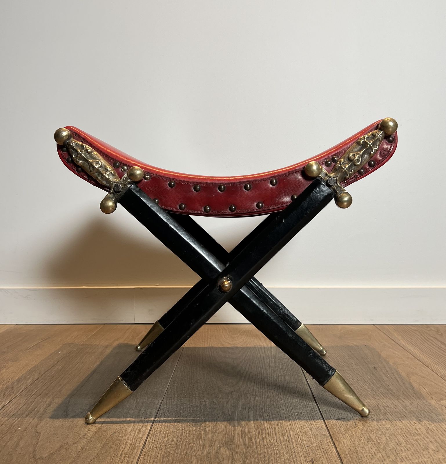photo vintage Neoclassical Style Curule Stool In Red Leather And Decorated With Crossed Swords In Bronze And Metal Covered In Black Leather