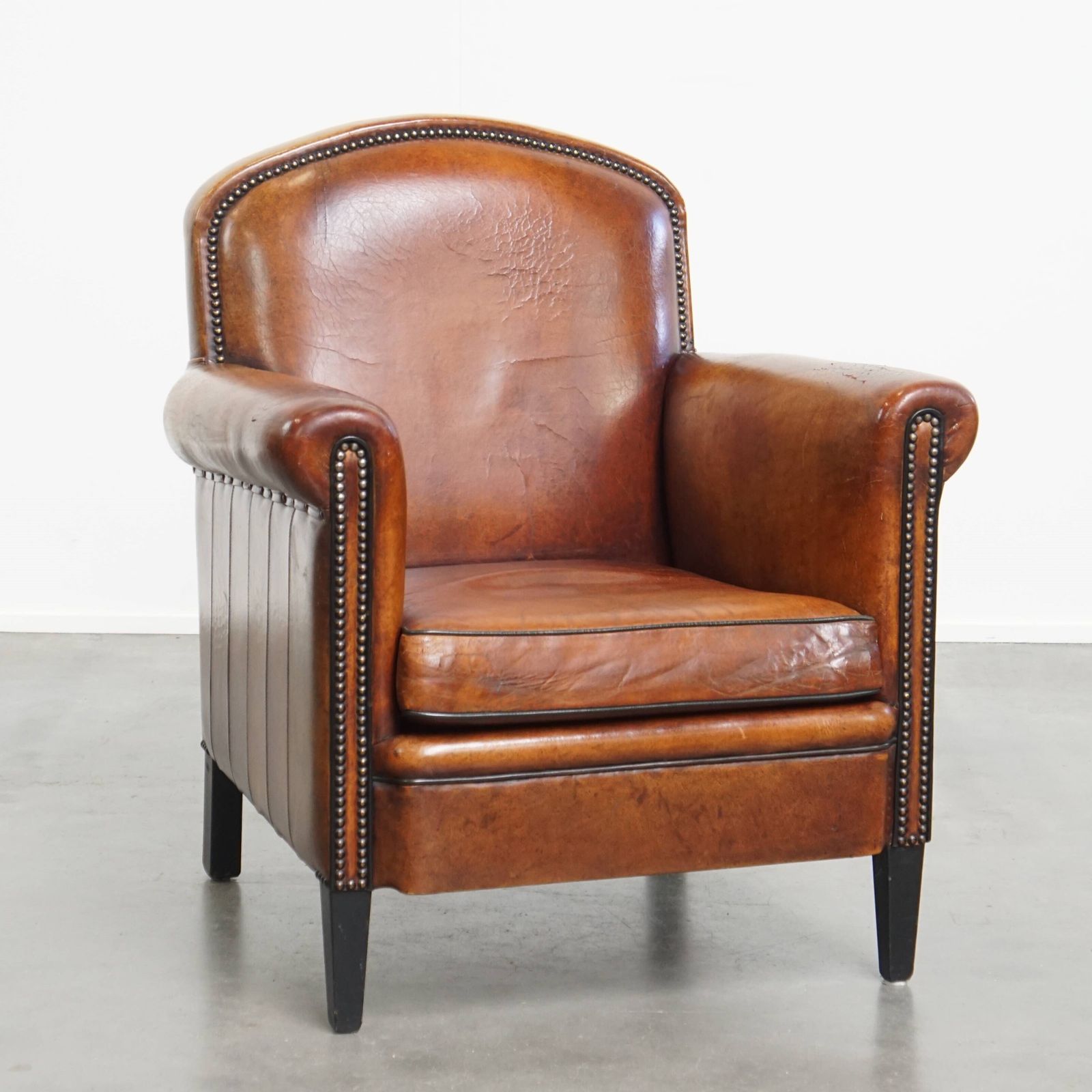 Stylish Sheepskin Designer Armchair In A Warm Cognac Color With A Finish Of Black Piping And Decorative Studs