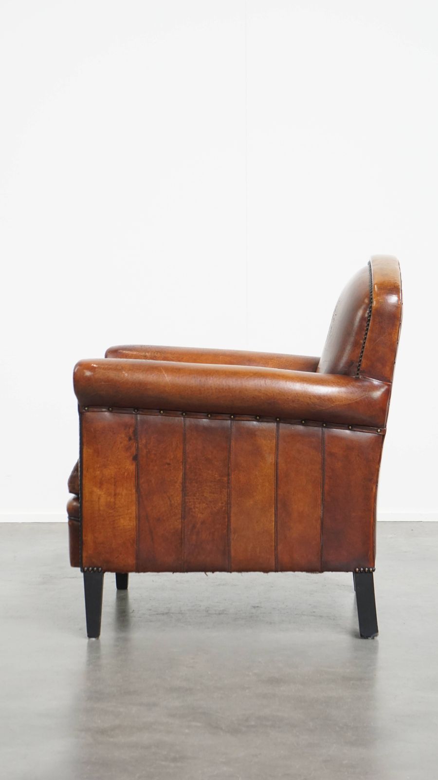 Stijlvolle Schapenvachten Fauteuil In Warm Cognackleur Met Zwarte Biezenafwerking En Decoratieve Sierspijkers photo 925.0