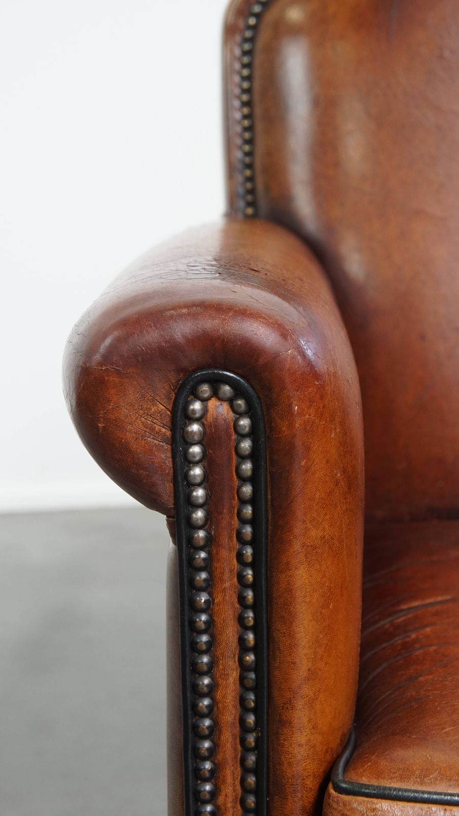 photo for sale Stylish Sheepskin Designer Armchair In A Warm Cognac Color With A Finish Of Black Piping And Decorative Studs