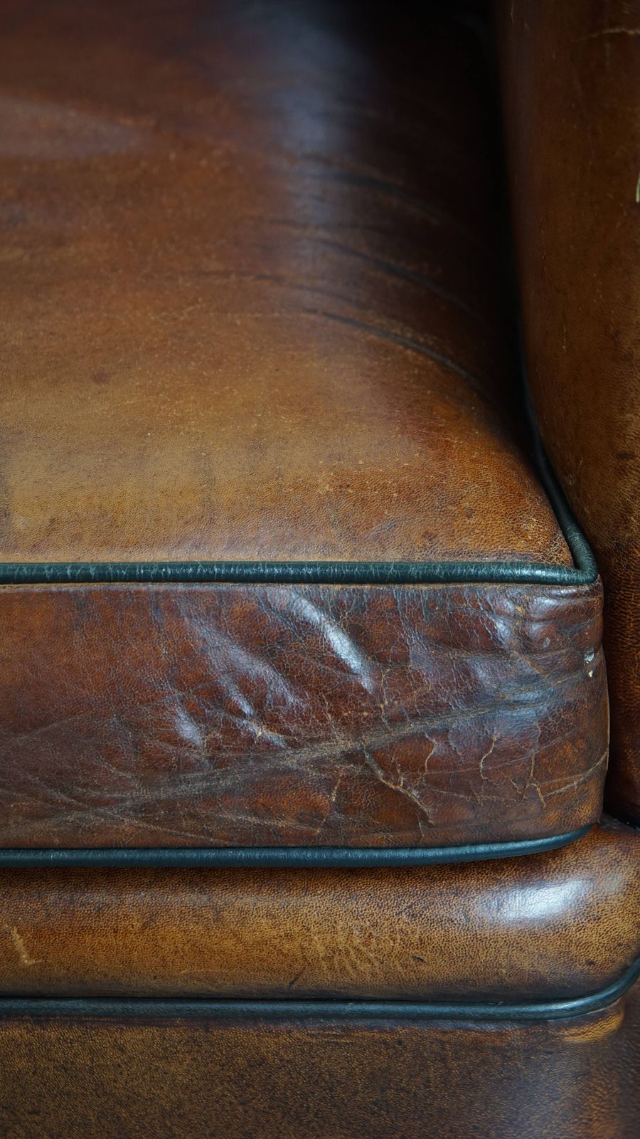 photo vinterior Stijlvolle Schapenvachten Fauteuil In Warm Cognackleur Met Zwarte Biezenafwerking En Decoratieve Sierspijkers