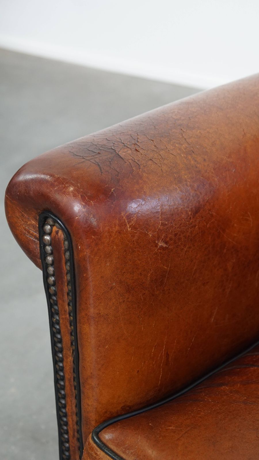 photo vintage Stijlvolle Schapenvachten Fauteuil In Warm Cognackleur Met Zwarte Biezenafwerking En Decoratieve Sierspijkers