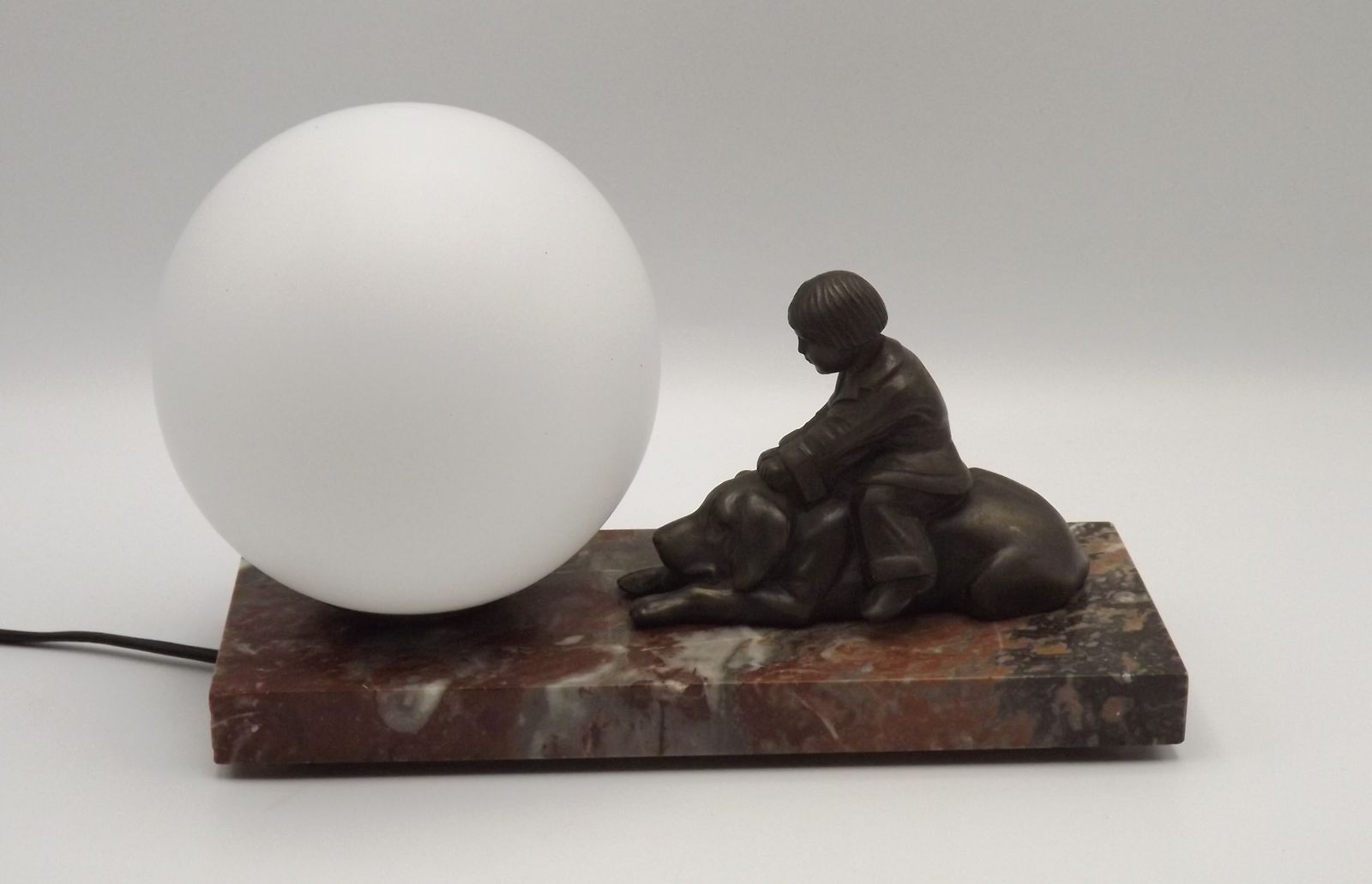 Verlichting Franse art deco tafellamp met bruinmarmeren voet, kind-en-hond-figuur en witte opaline glazen bolkap photo