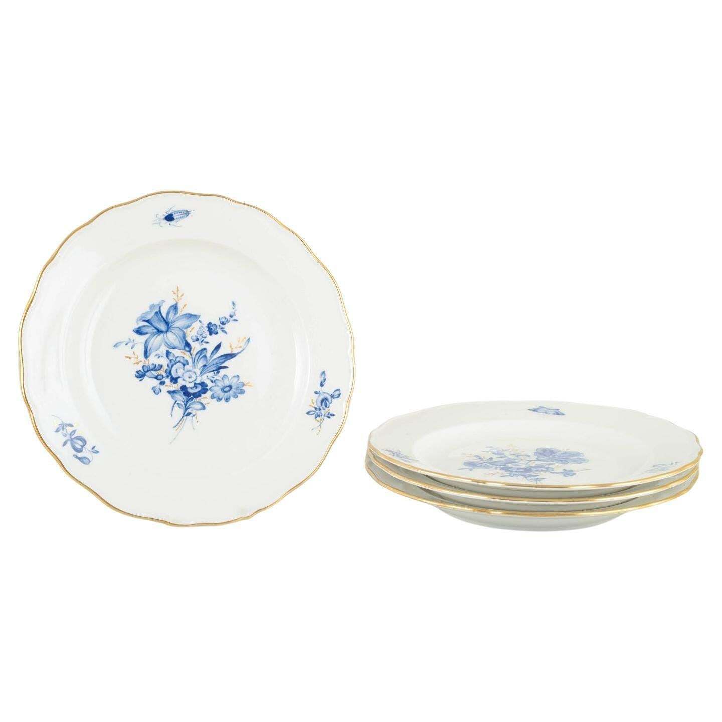 Meissen. 4 assiettes à déjeuner en porcelaine à motifs floraux bleus et liseré doré.