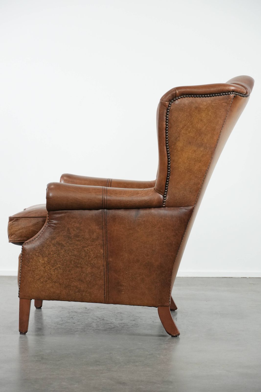 Tijdloze Cognackleurige Oorfauteuil In Engelse Stijl, Bekleed Met Koeienleer En Afgewerkt Met Decoratieve Sierspijkers En Fraaie Details. photo 809.0