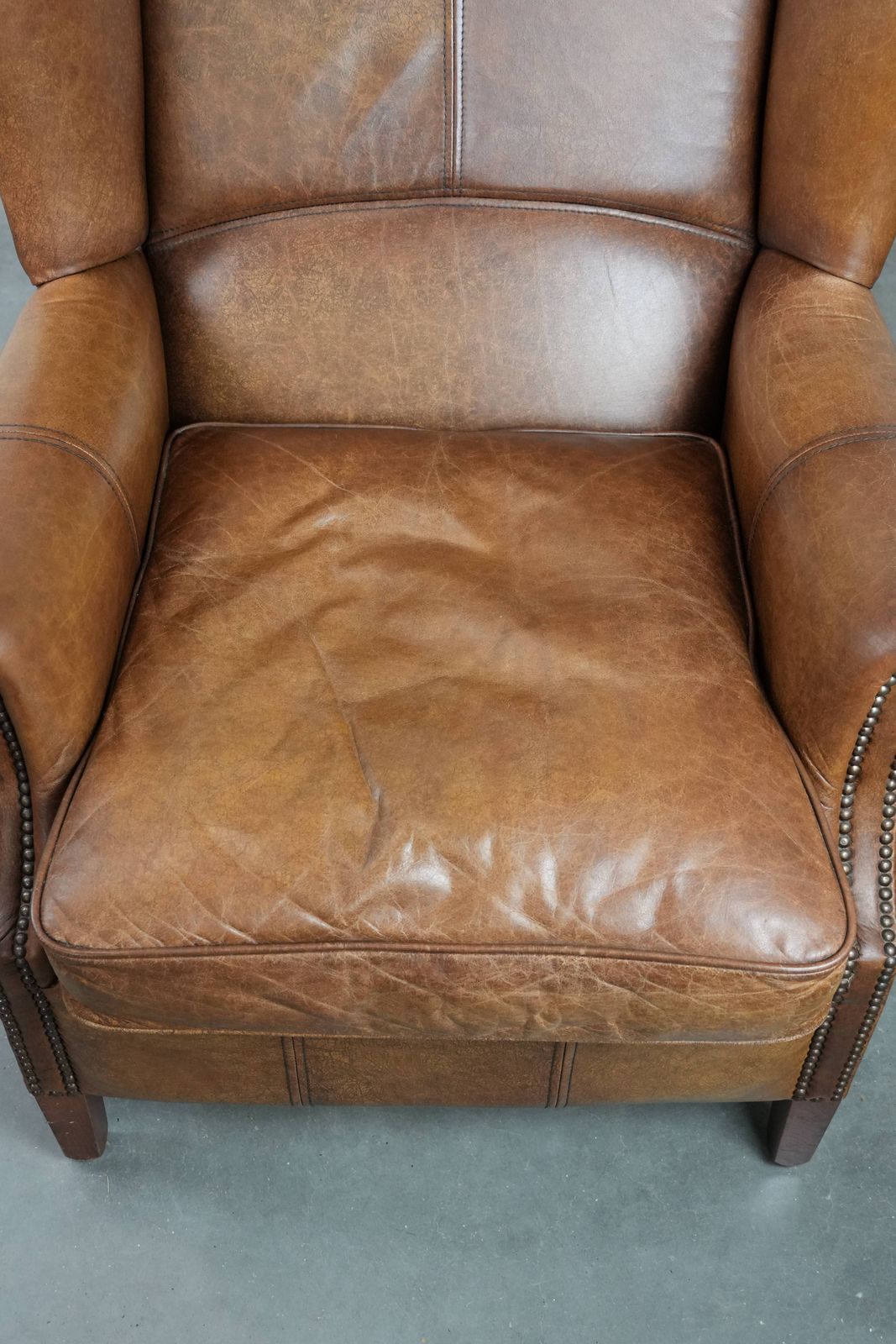 Timeless Cognac Colored Wing Armchair In English Style Made Of Cowhide Leather, Finished With Decorative Studs And Beautiful Details. photo vinterior