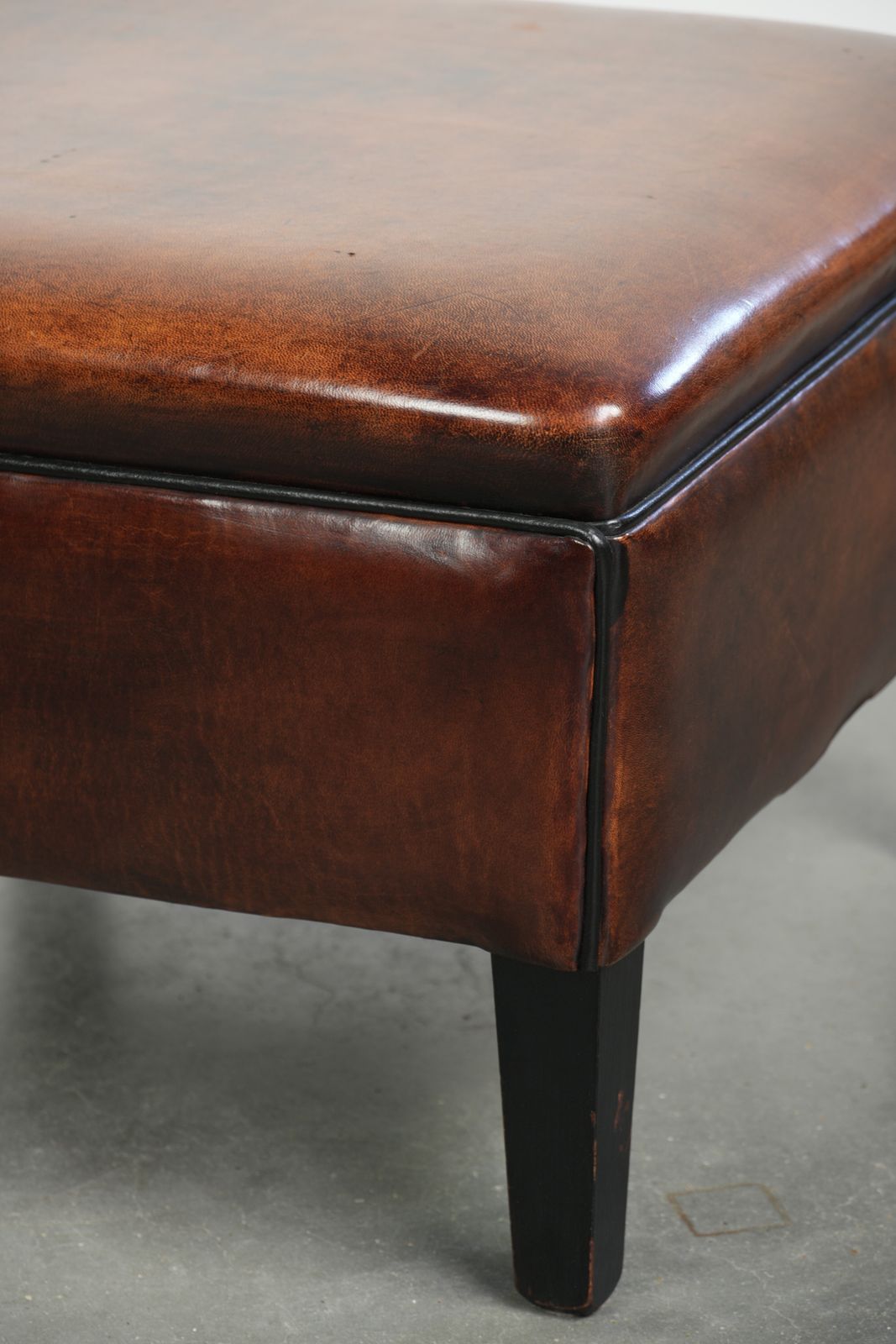 photo furniture Grote Donkerbruine Vierkante Ottoman Van Schapenvacht Met Zwart Biesje