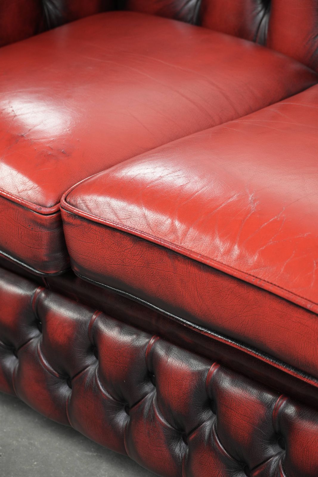 photo buy Engelse Chesterfield 2,5/3-zitsbank van koeienleer in een luxueuze rode kleur.