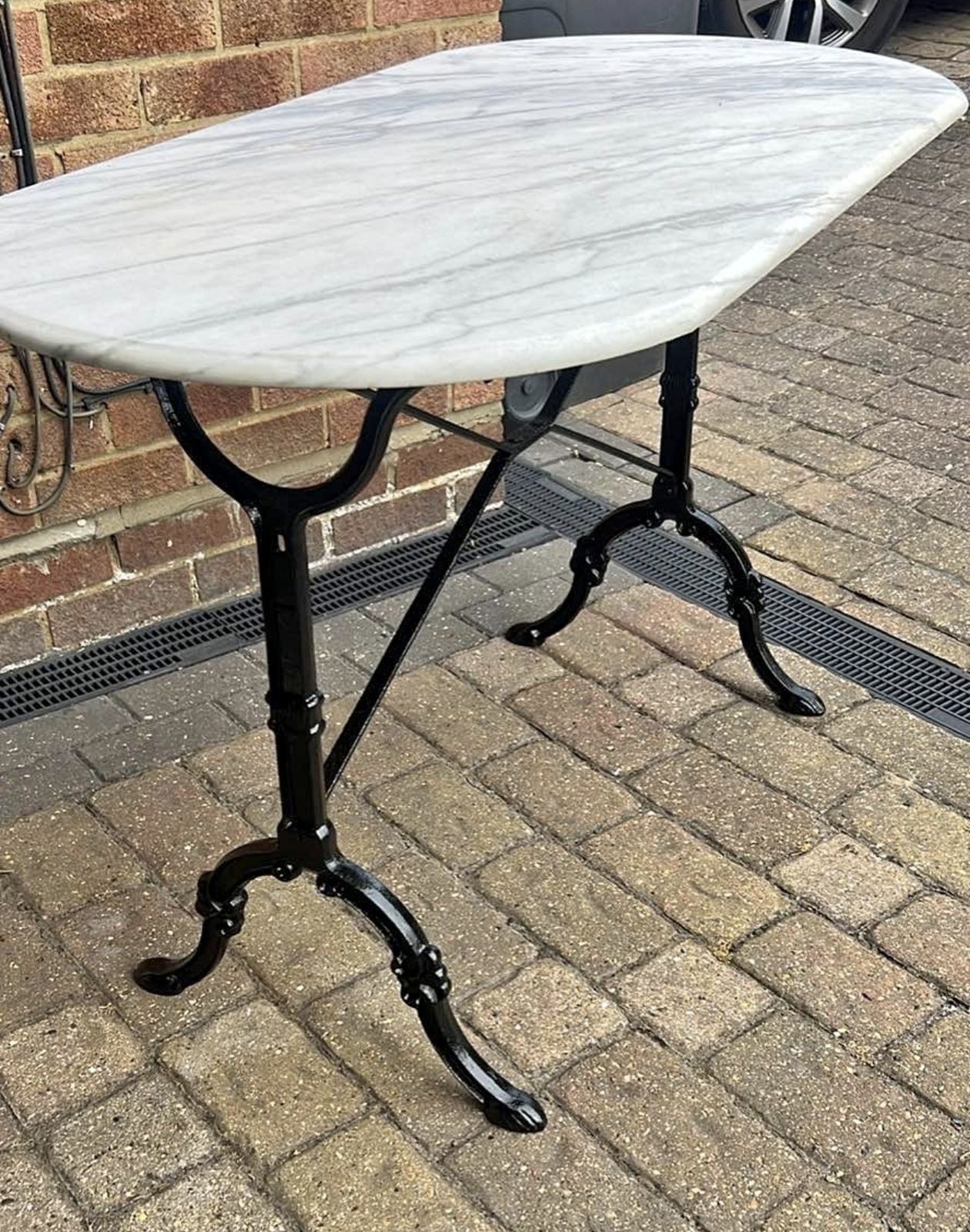 Antique Style Bistro Table Features An Oval White Marble Top Resting On A Black Cast Iron Base. photo for sale