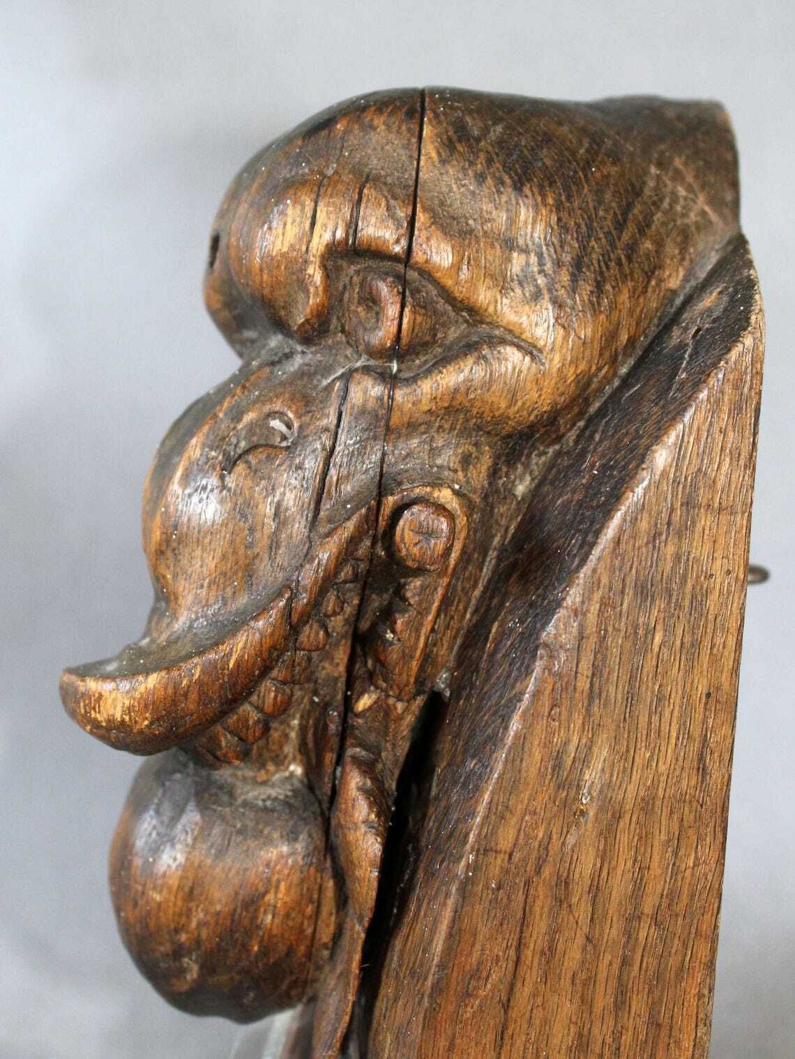 Groot antiek houten ornament in de vorm van een slangenkop met tanden die een appel of granaatappel eet, driedimensionaal, handgesneden, gotische architectuur photo furniture