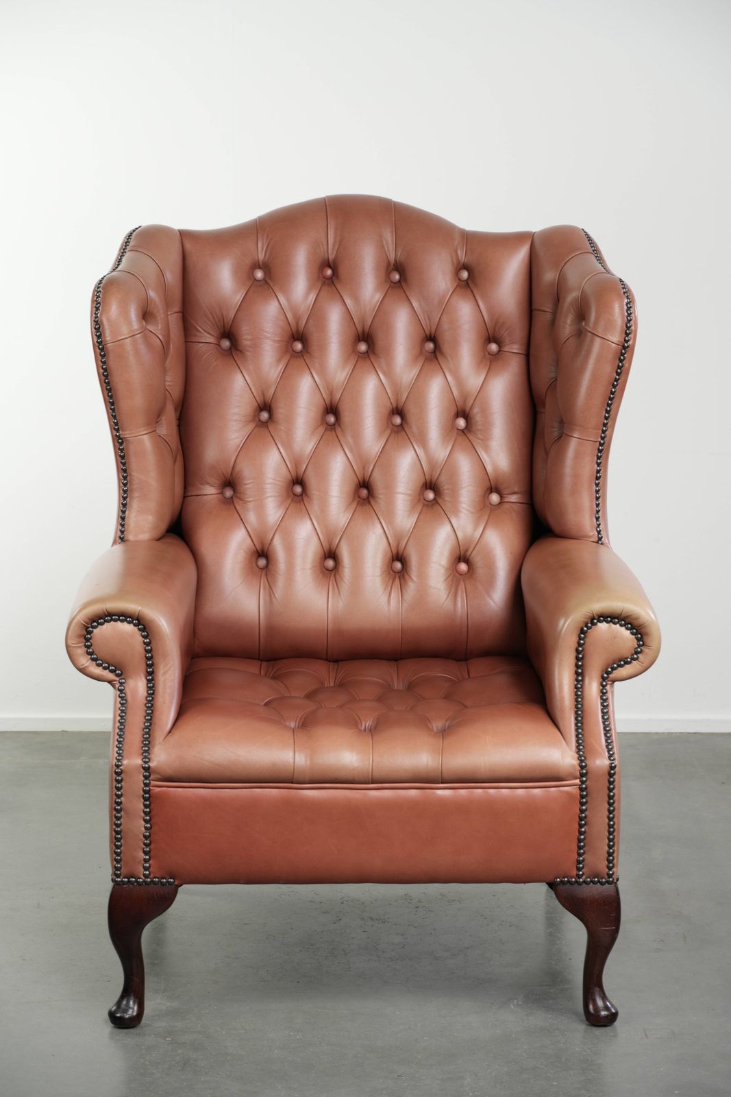 Klassieke Engelse Chesterfield-vleugelfauteuil met koeienhuid, knoopsluiting, mooie patina en fraaie kleuren. photo furniture