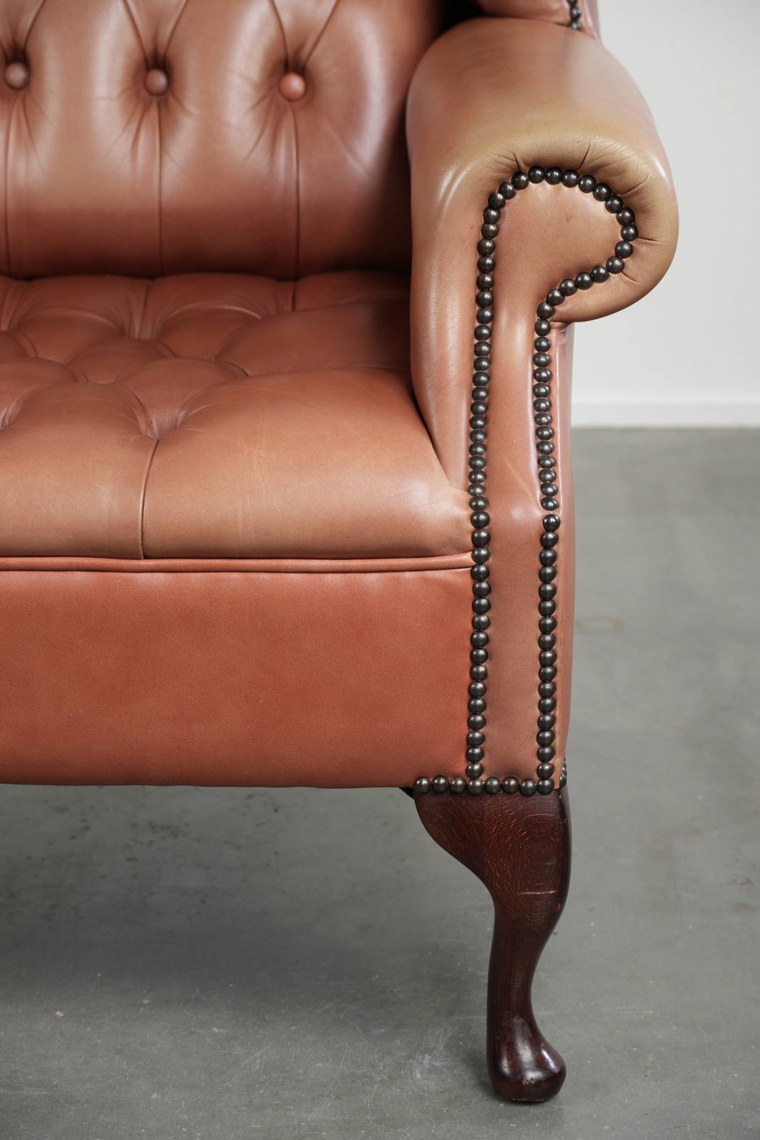 photo for sale Klassieke Engelse Chesterfield-vleugelfauteuil met koeienhuid, knoopsluiting, mooie patina en fraaie kleuren.