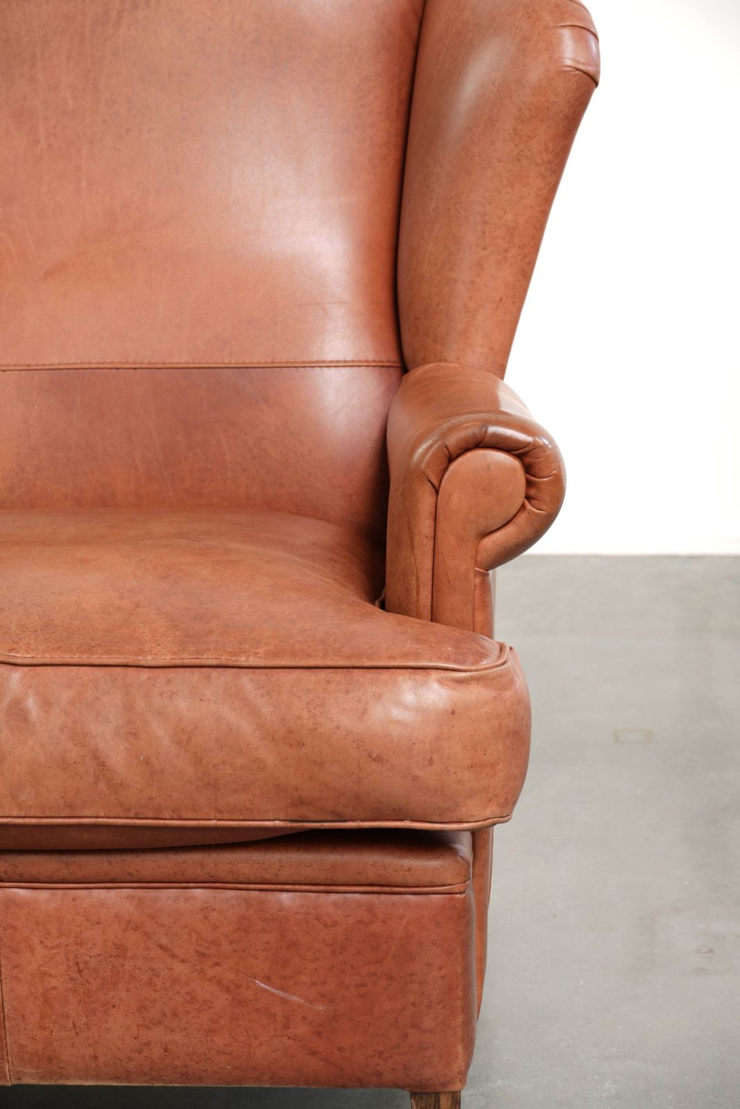 photo for sale Light Cognac Colored Cowhide Wing Armchair With Matching Piping And A Characterful English Look.