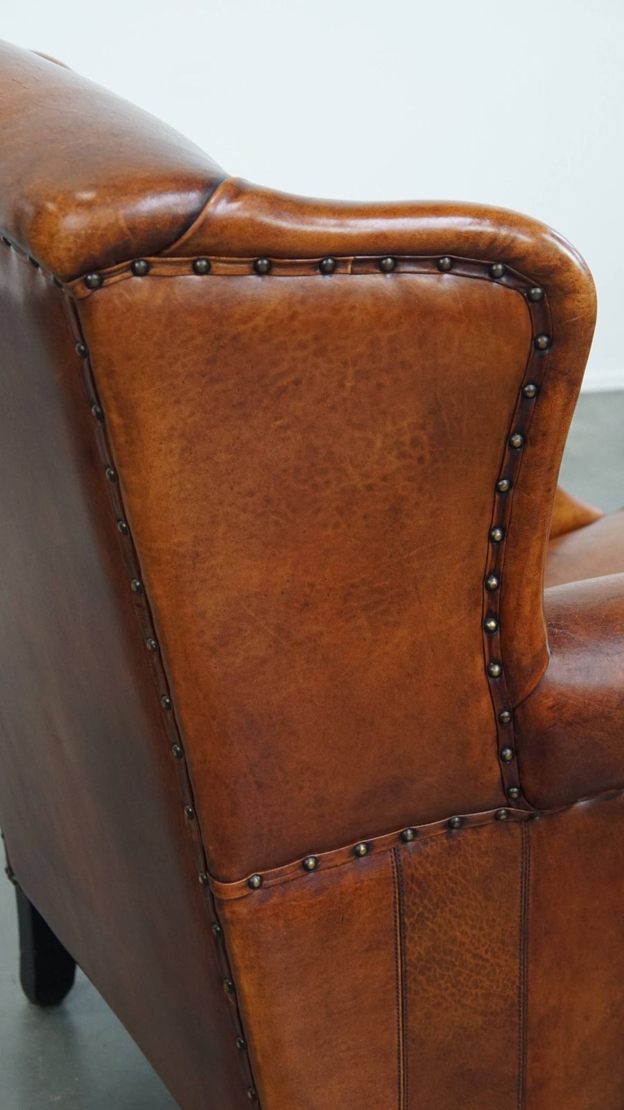 photo buy Comfortabele schapenvachten oorfauteuil met warme kleurstelling en afwerking met stiksels en zwart biesje.