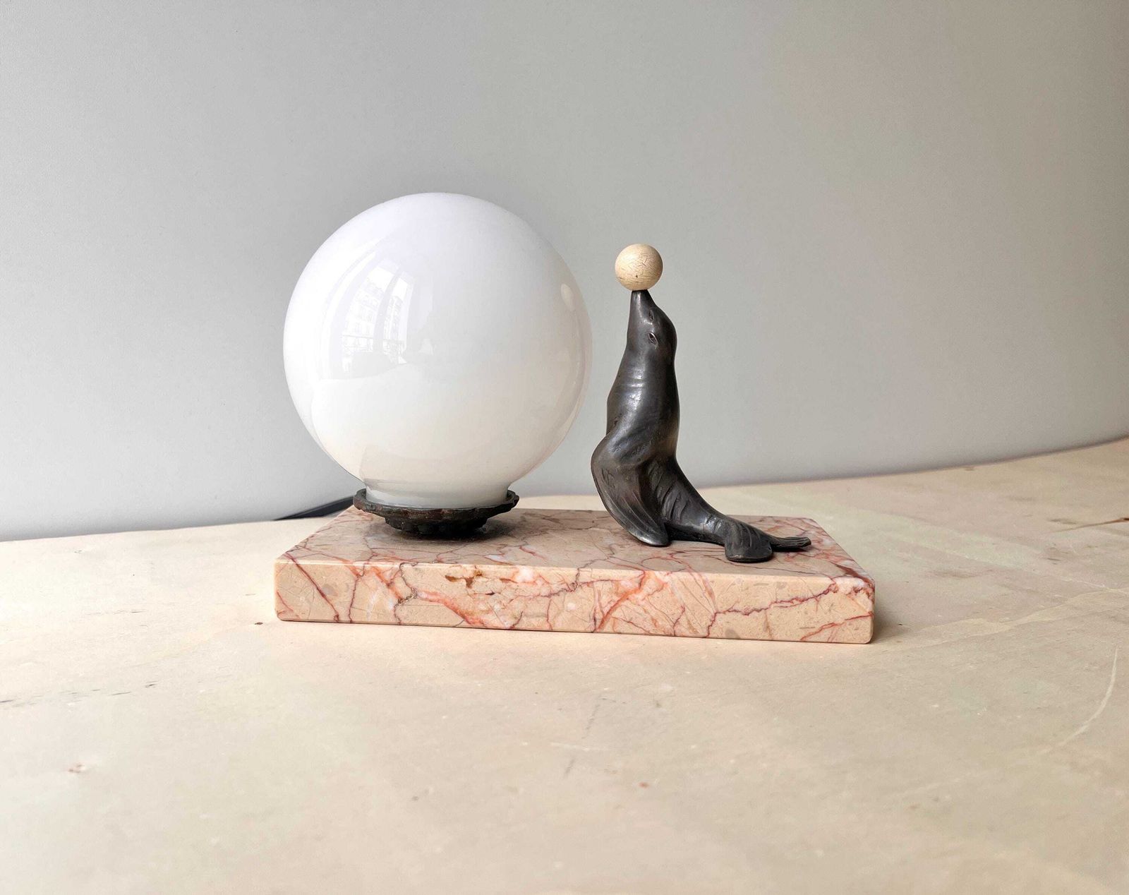 Antiek art deco tafellampje in marmer en spelter, "The Sea Lion Playing With Balloon", bolverlichting jaren 1930