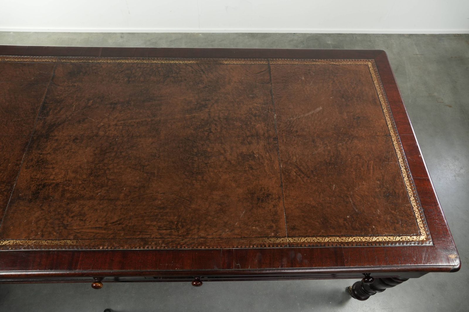 Antiek Engels schrijfbureau uit de eind 19e eeuw met een warme houtkleur en een donkerbruin lederen blad met gouden accenten. photo vintage