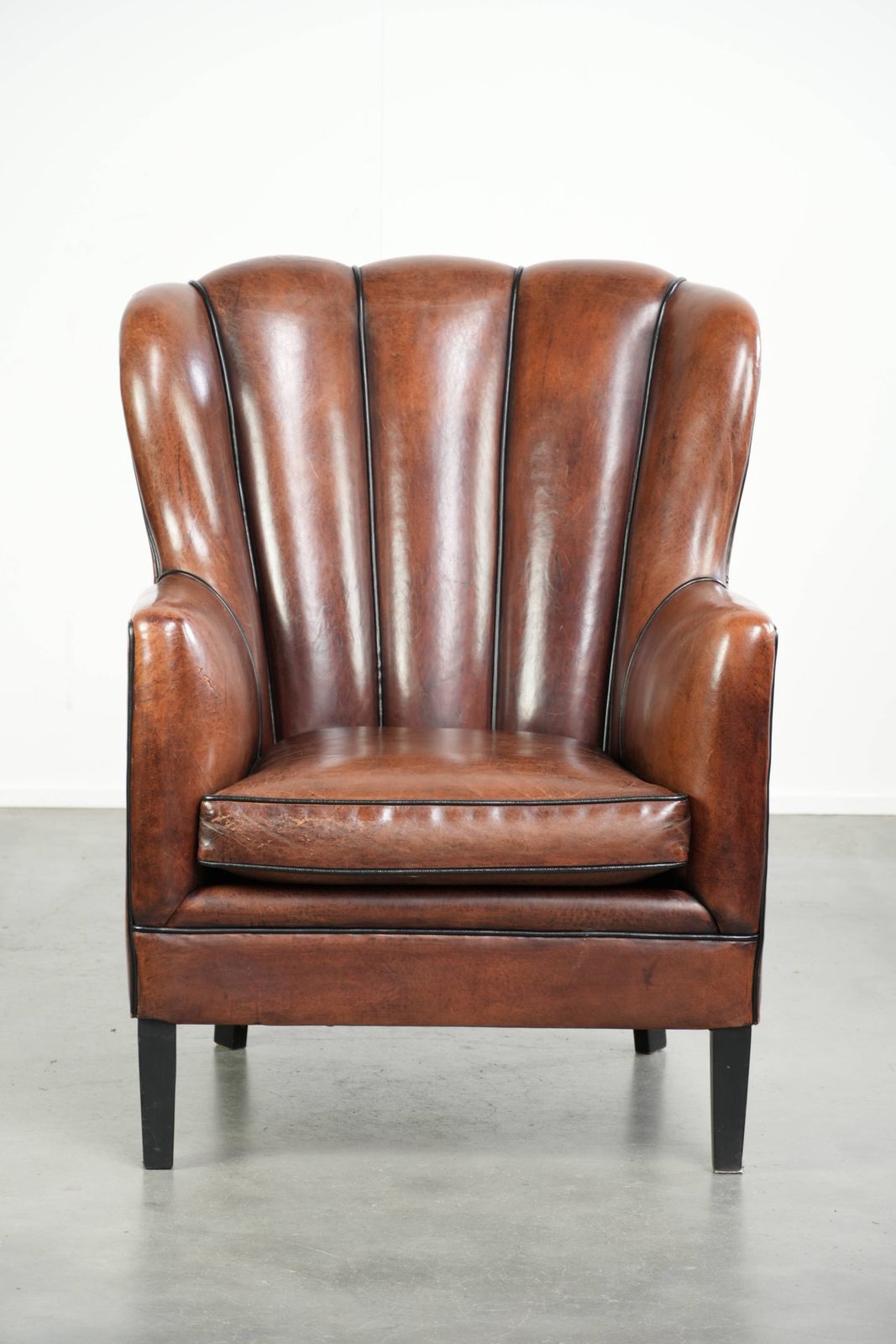 Unieke schapenleren fauteuil met warme, diepe kleuren, afgewerkt met zwarte biezen photo furniture