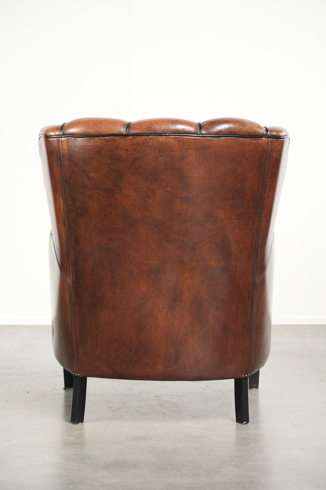 Unieke schapenleren fauteuil met warme, diepe kleuren, afgewerkt met zwarte biezen photo Meubels