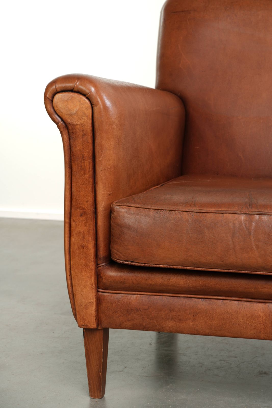 photo furniture Stevige Vintage Schapenvacht Fauteuil Met Een Mooie Cognackleur En Een Comfortabele Zitting