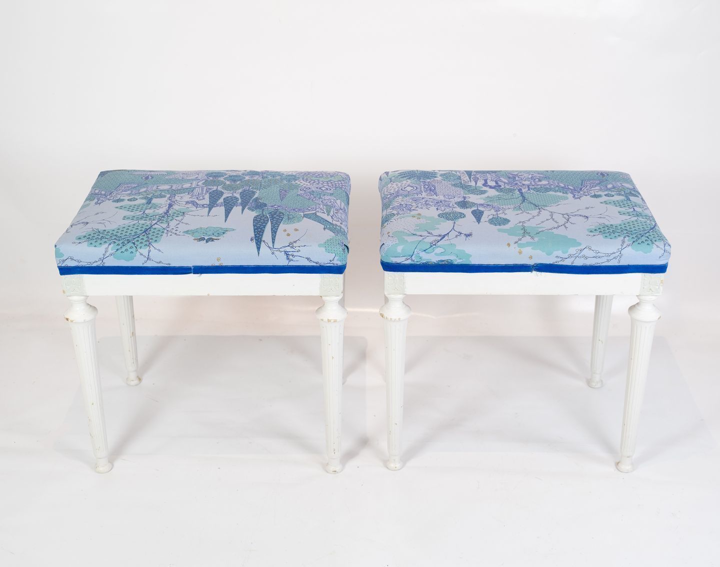 A Set Of 2 Antique Stools With White Painted Wood And Upholstered With Blue Fabric From The 1920s.