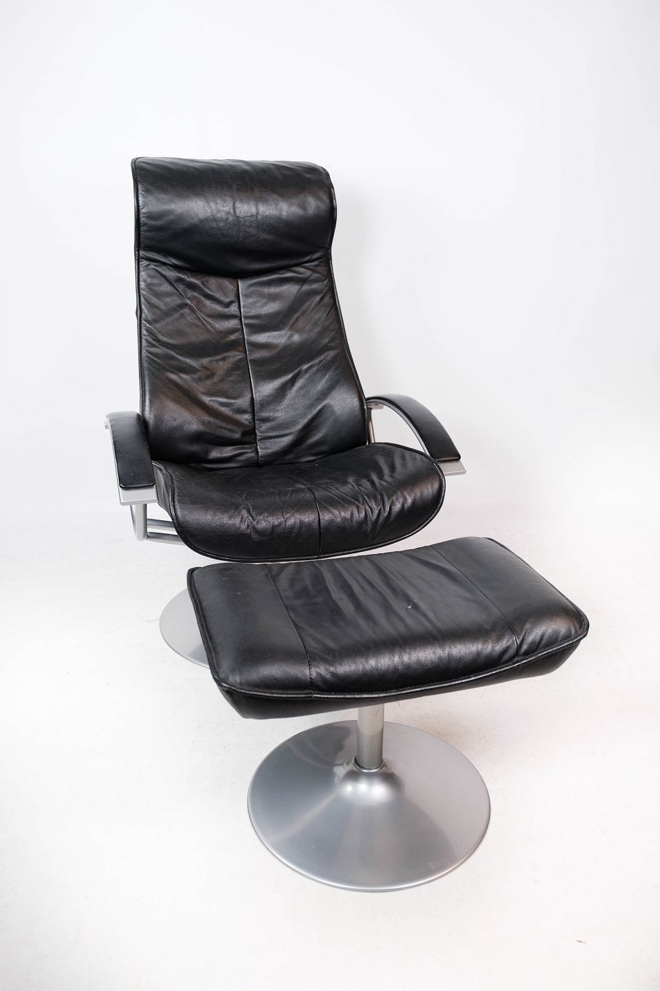 Armchair With Stool Upholstered In Black Leather And Metal Frame, By Danish Design From The 1970s.