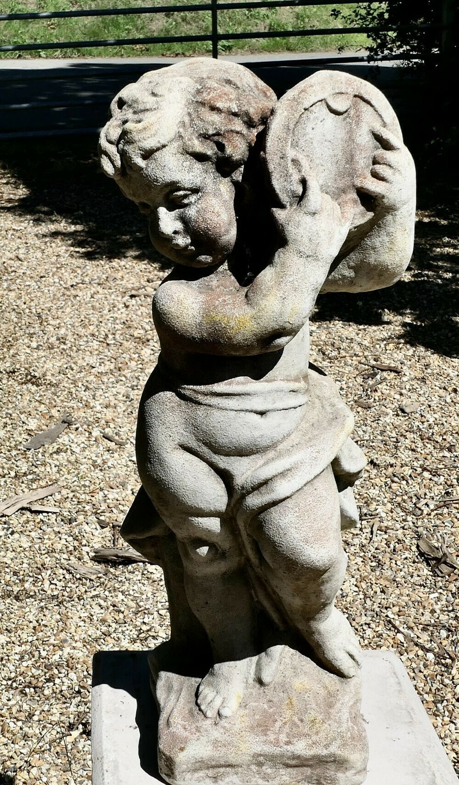 Old Weathered Statue Of A Putti Playing Tambourine