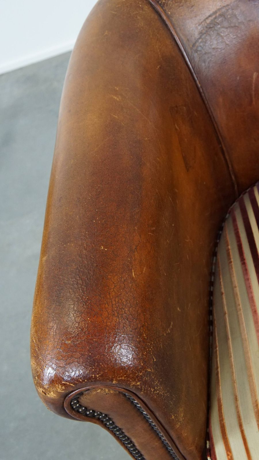 Karaktervolle Vintage Clubfauteuil Van Schapenleer In Cognackleur Met Kleurrijk Stoffen Zitkussen photo buy