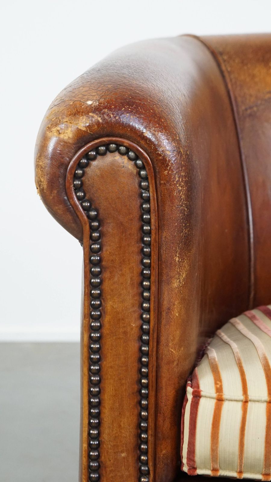 photo buy Characterful Vintage Cognac Colored Club Chair Made Of Sheepskin With A Colorful Fabric Seat Cushion
