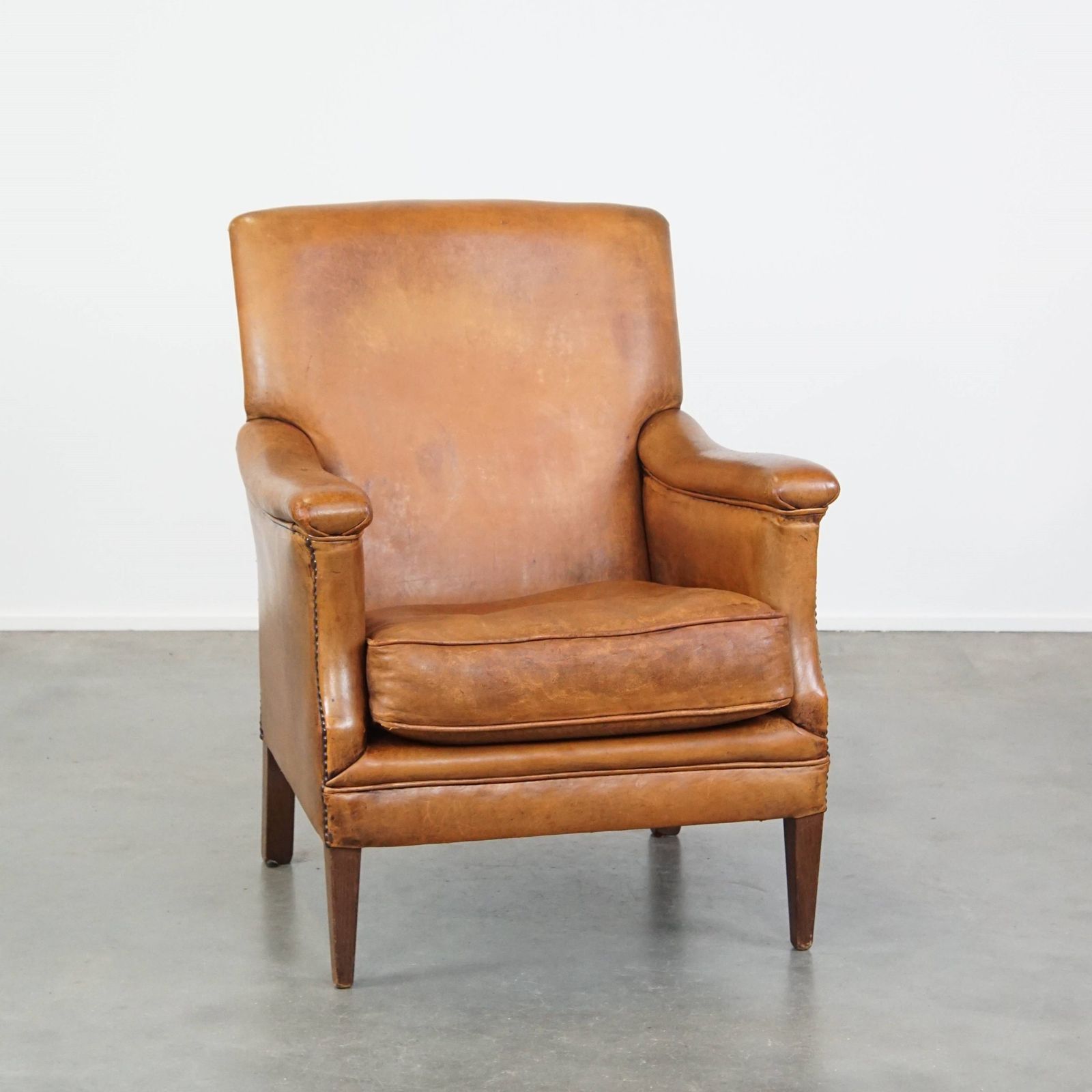 Characteristic And Comfortable Cognac Colored Sheepskin Armchair With Straight Shapes And A Beautiful Patina