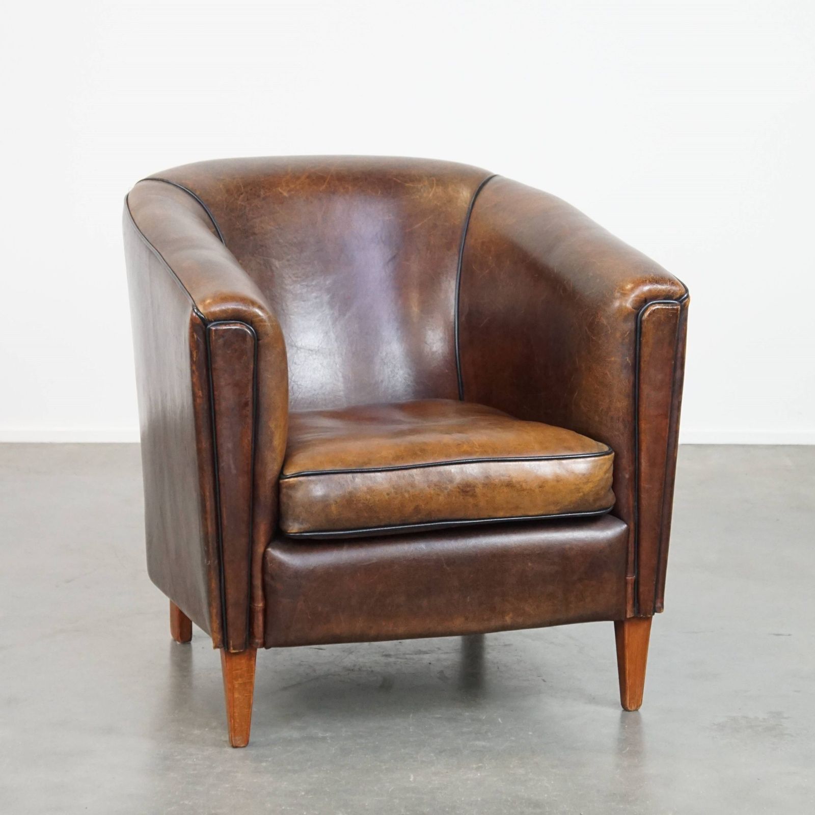 Donkere En Strakke Clubfauteuil Van Schapenvacht Met Mooie Kleuren En Zwarte Paspelafwerking