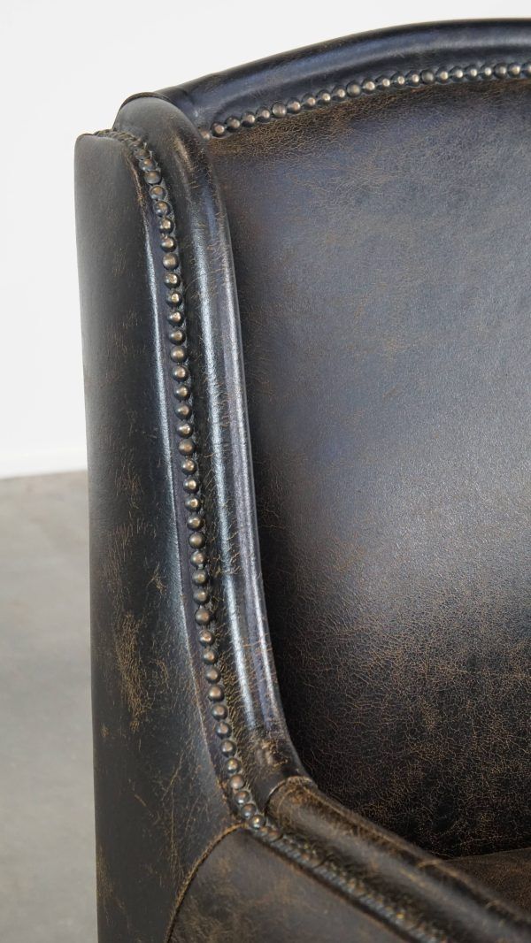 photo furniture Karaktervolle, Stevige Fauteuil In Zwart Koeienhuid Met Hoge Rug En Decoratieve Siernagels, Industriële Stijl