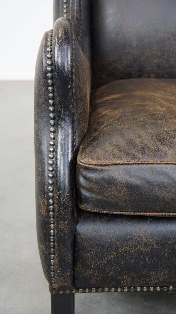 photo for sale Karaktervolle, Stevige Fauteuil In Zwart Koeienhuid Met Hoge Rug En Decoratieve Siernagels, Industriële Stijl