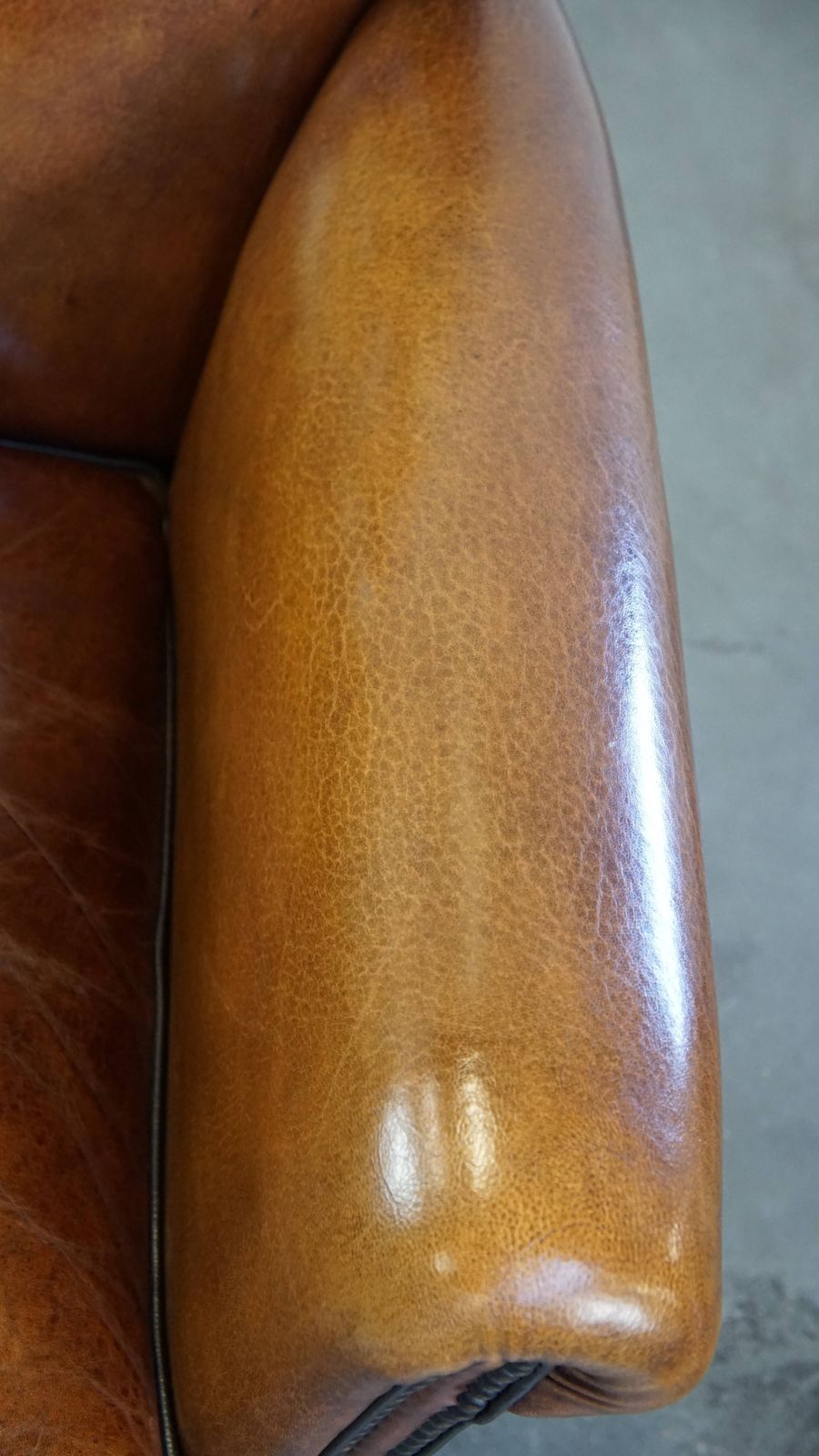 photo furniture Goed onderhouden schapenleren design fauteuil, luxueus afgewerkt met siernagels en zwart biesje