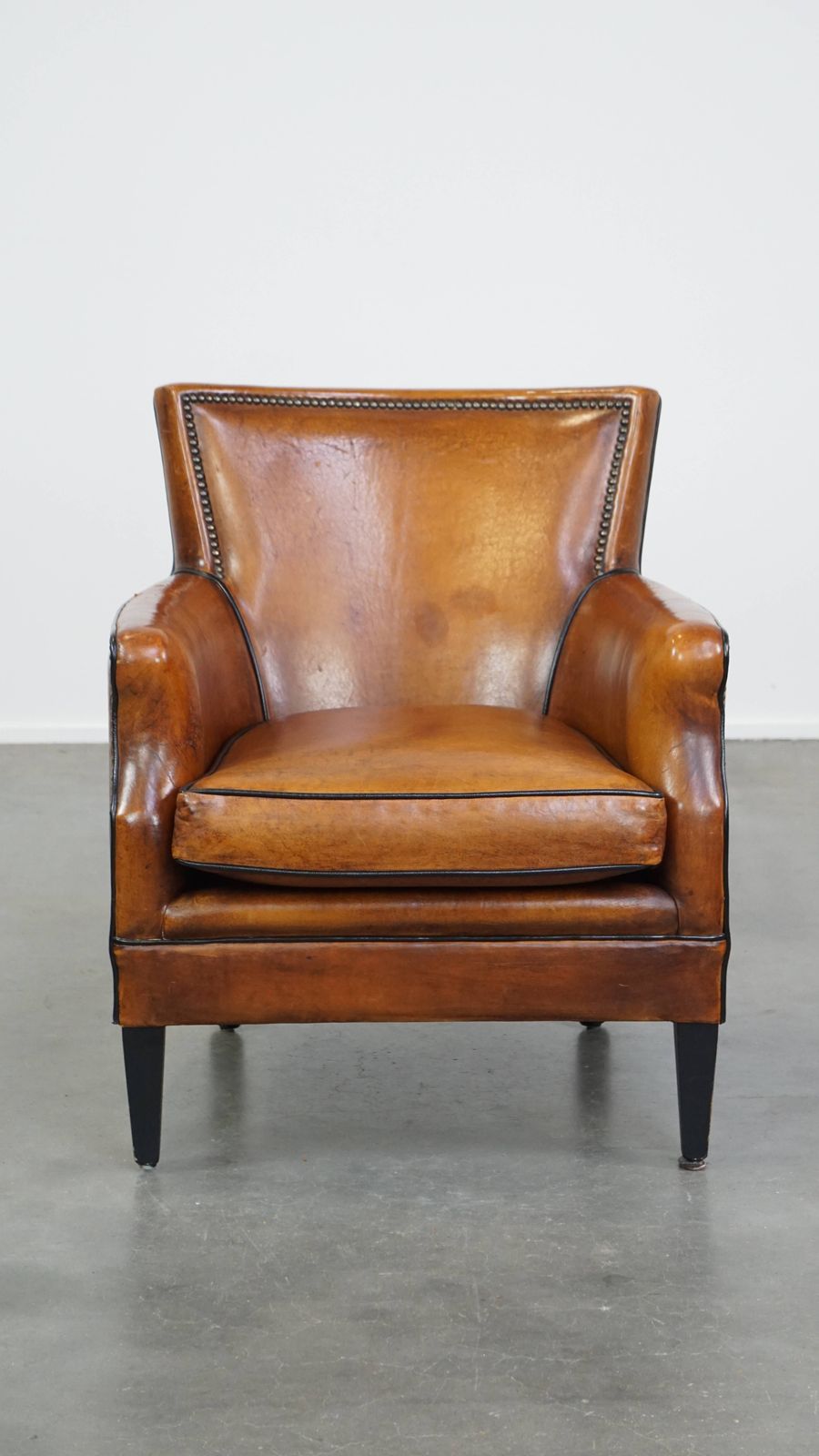 Subtle Cognac Colored Sheepskin Armchair With A Nice Design And Finish With Black Piping And Decorative Nails photo furniture