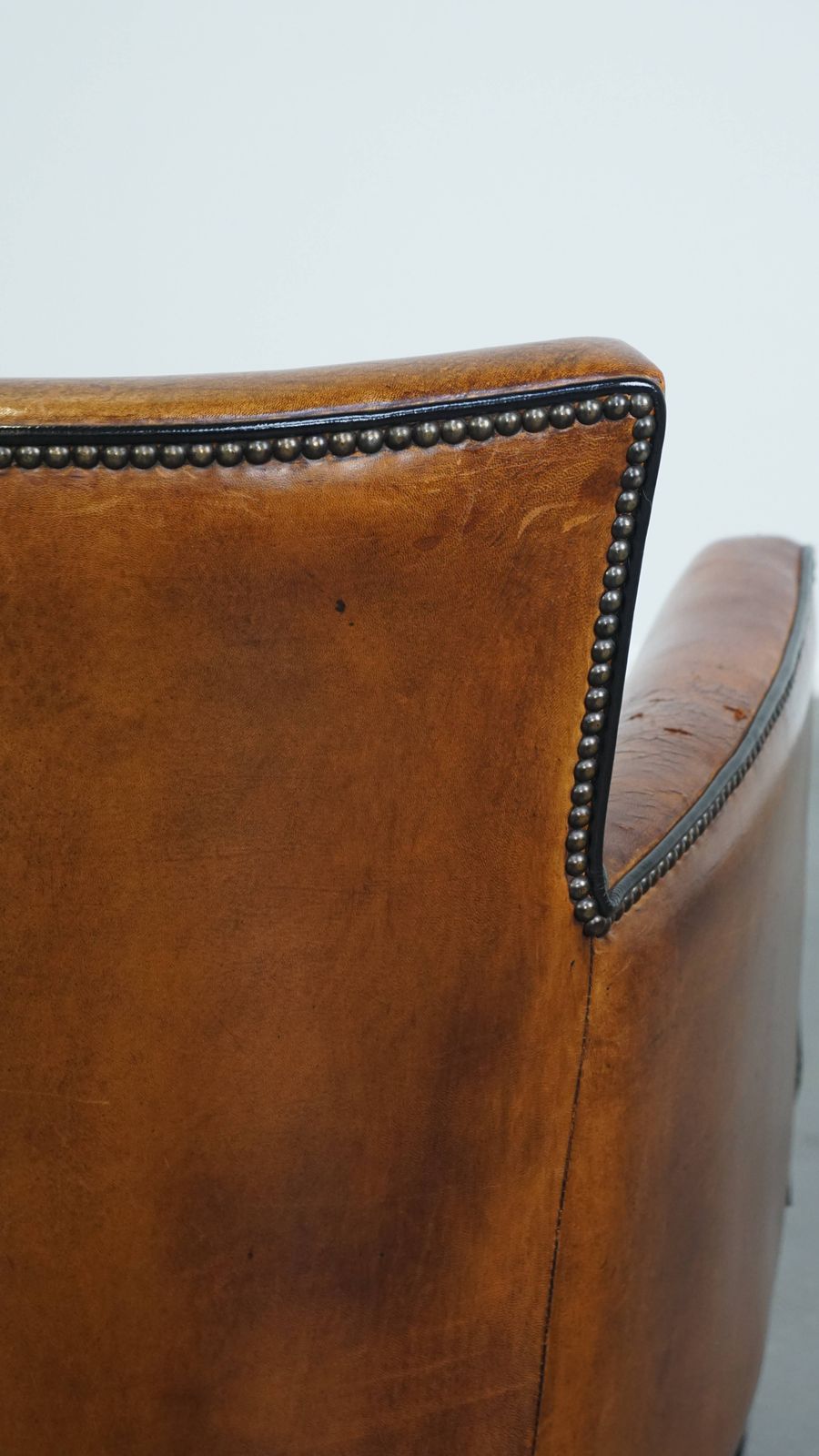 photo vinterior Subtle Cognac Colored Sheepskin Armchair With A Nice Design And Finish With Black Piping And Decorative Nails