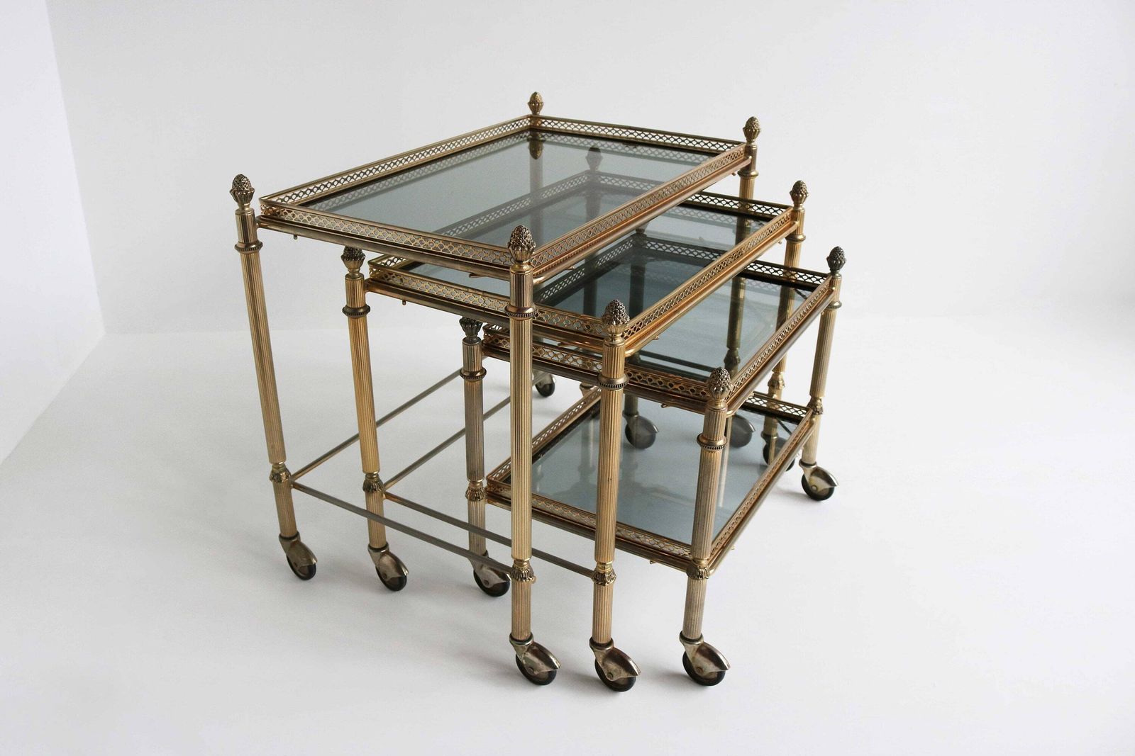 Neoclassische Franse Bijzettafels In Maison Baguès Stijl – Mid Century Gerookt Glas, Set Van 3 Vintage Bijzettafels Op Wieltjes, Ca. 1960