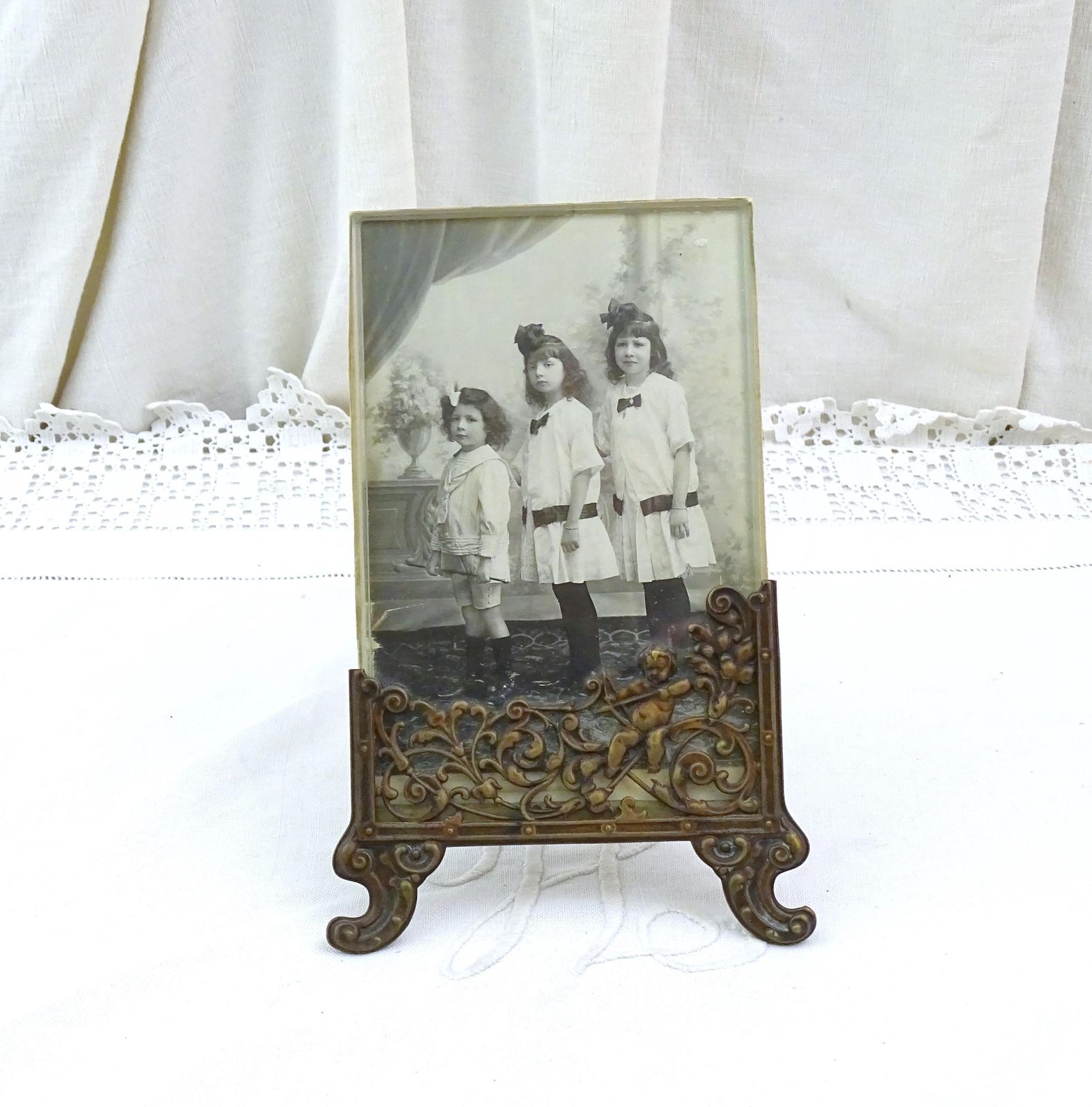 Antieke Franse Vrijstaande Fotolijst Met Cherub In Bronskleurig Reliëfmetaal En Zwart Witfoto Van Zusjes En Broertje