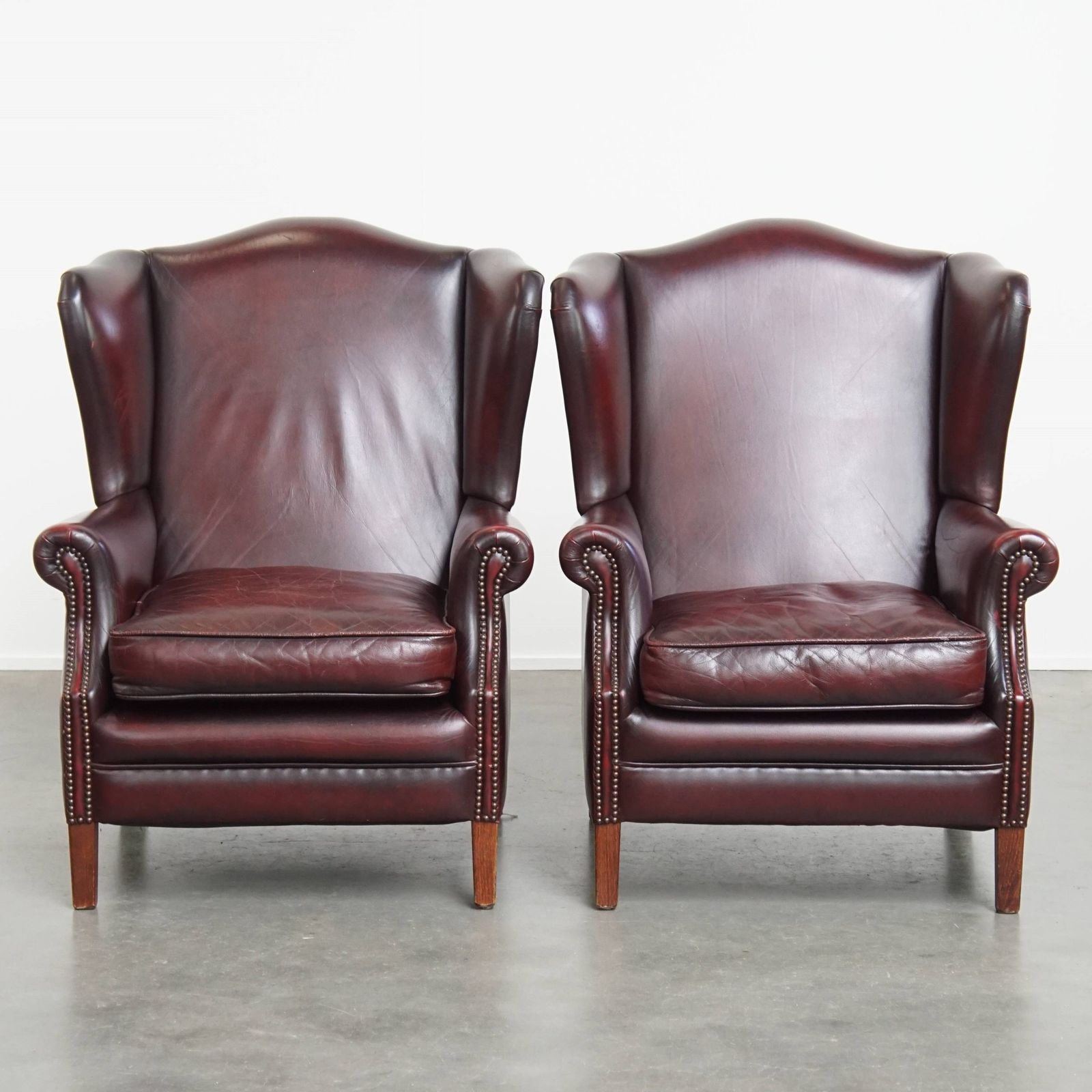 Set Of 2 Beautiful And Comfortable Burgundy Red Cowhide Wing Chairs In English Style With A Beautiful Patina