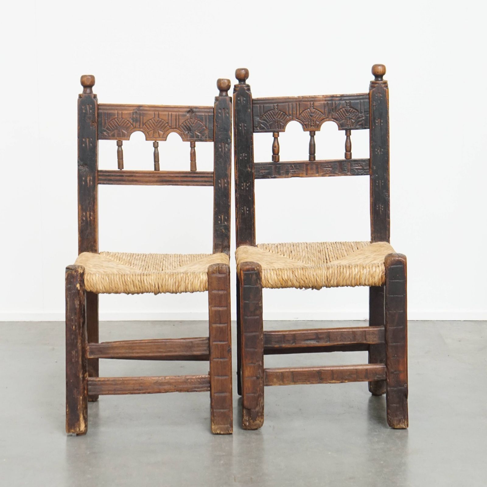 Nice Unique Set Of 2 Antique Spanish Farm Chairs With Woven Wicker Seat And Beautiful Wood Carving
