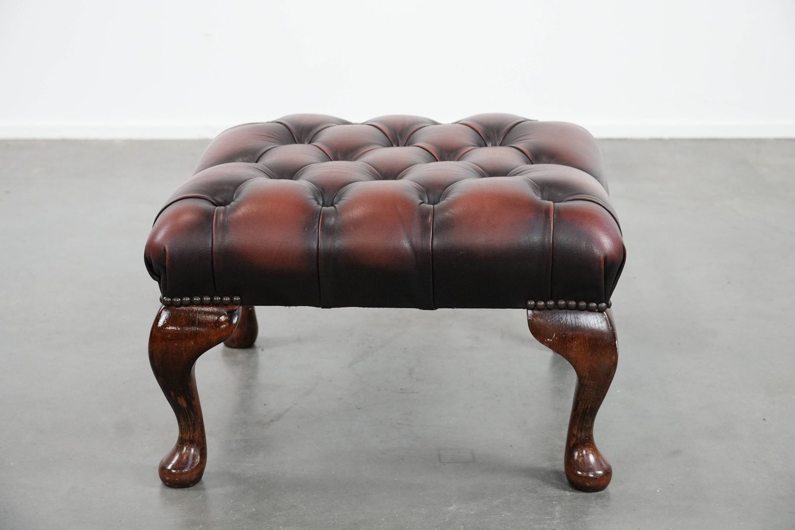 Elegante Donkerbruine Chesterfield Voetenbank Van Koeienhuid photo Meubels