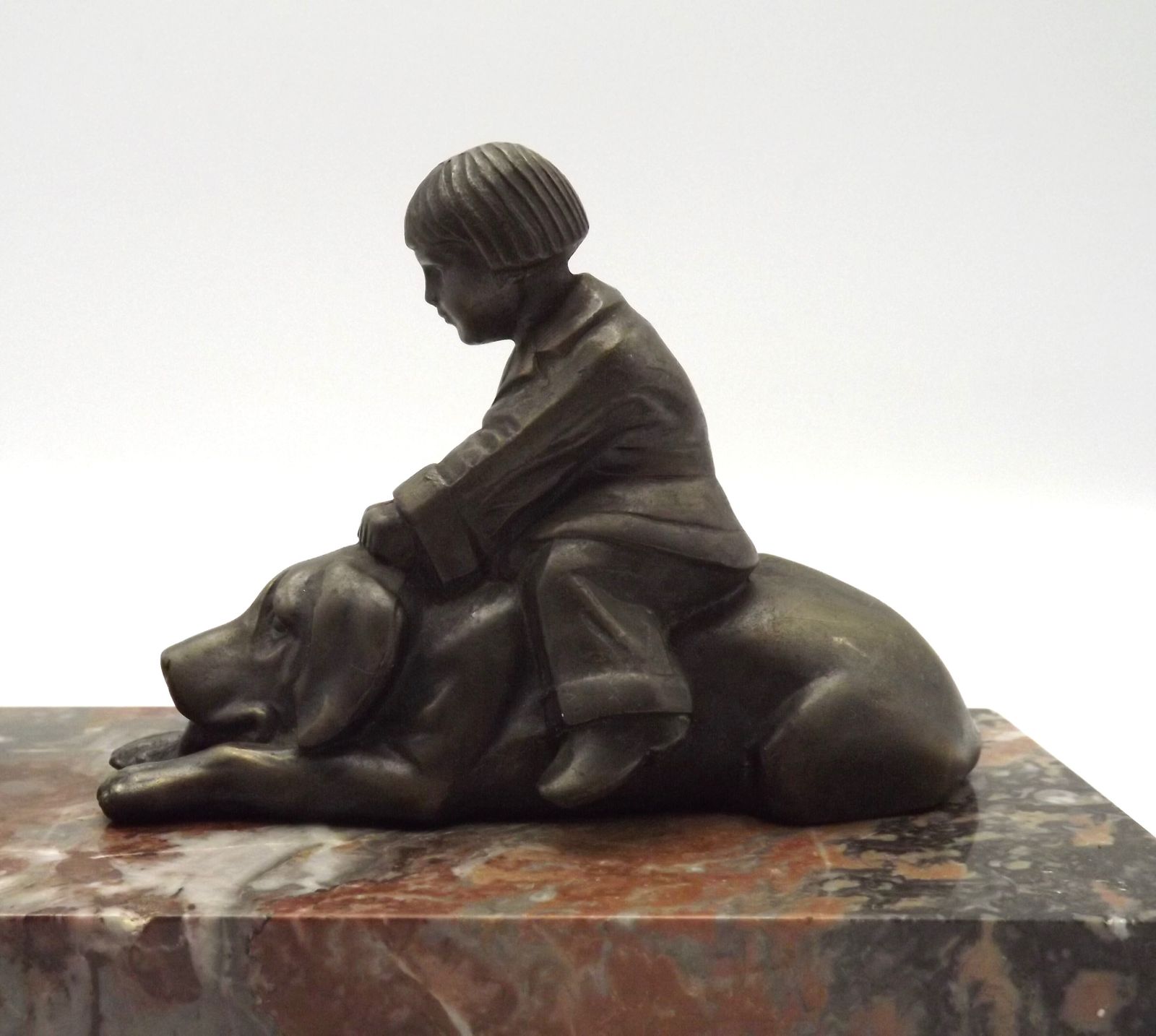 Franse art deco tafellamp met bruinmarmeren voet, kind-en-hond-figuur en witte opaline glazen bolkap