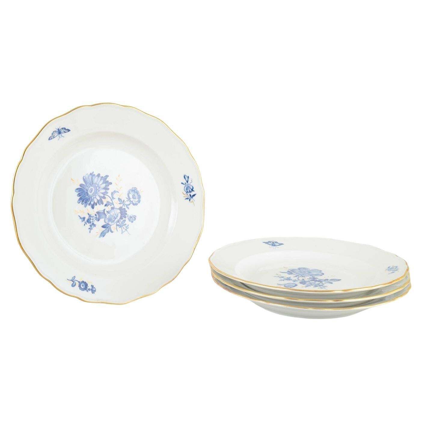 Meissen. 4 assiettes de table en porcelaine à motifs floraux bleus et liseré doré.