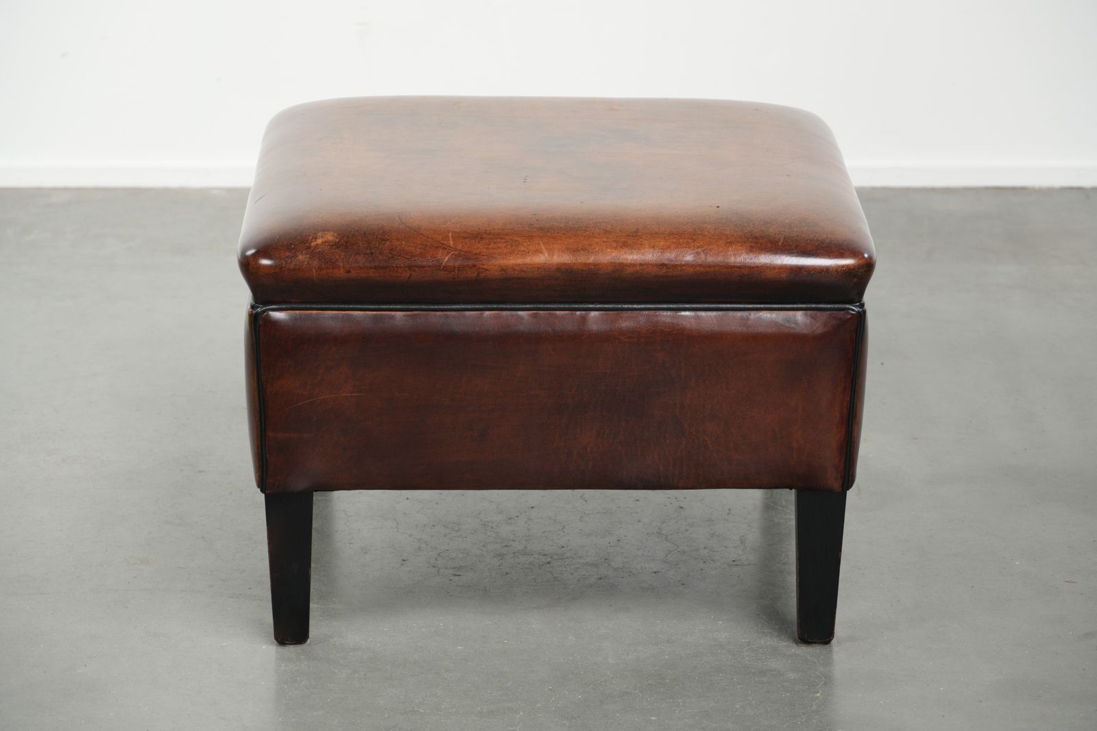 Grote Donkerbruine Vierkante Ottoman Van Schapenvacht Met Zwart Biesje photo for sale