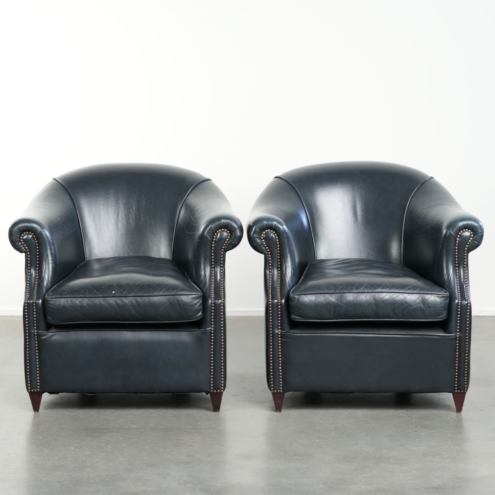 Set van twee donkerblauwe lederen club fauteuils met een tijdloos design