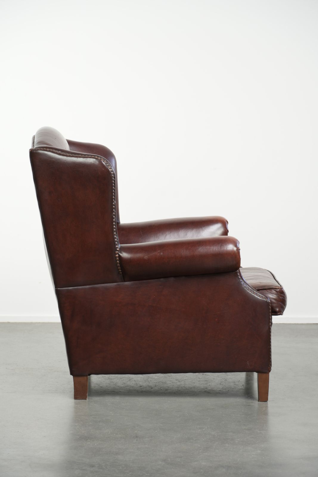 Elegante Vintage Schapenvacht Vleugelfauteuil Met Een Tijdloze Engelse Uitstraling, Afgewerkt Met Decoratieve Sierspijkers. photo for sale