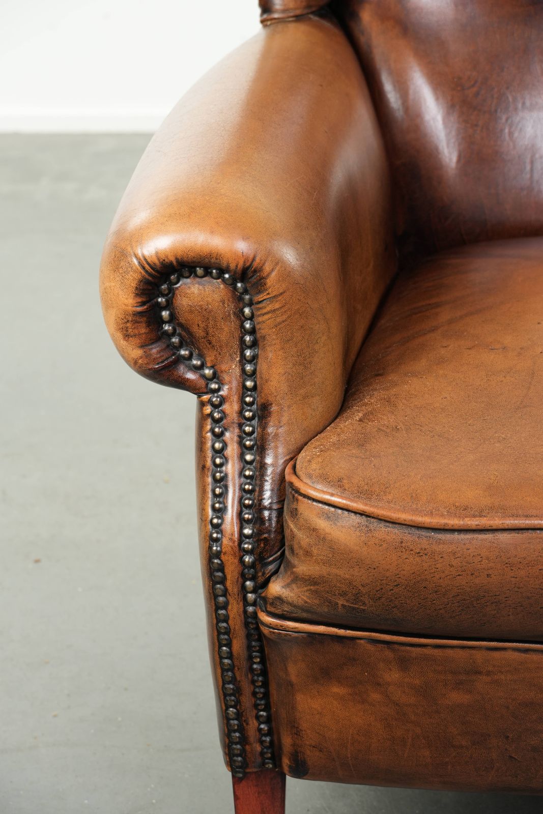 photo furniture Comfortable Wing Armchair Made Of Sheepskin Finished With Decorative Studs And A Characterful English Style Appearance.
